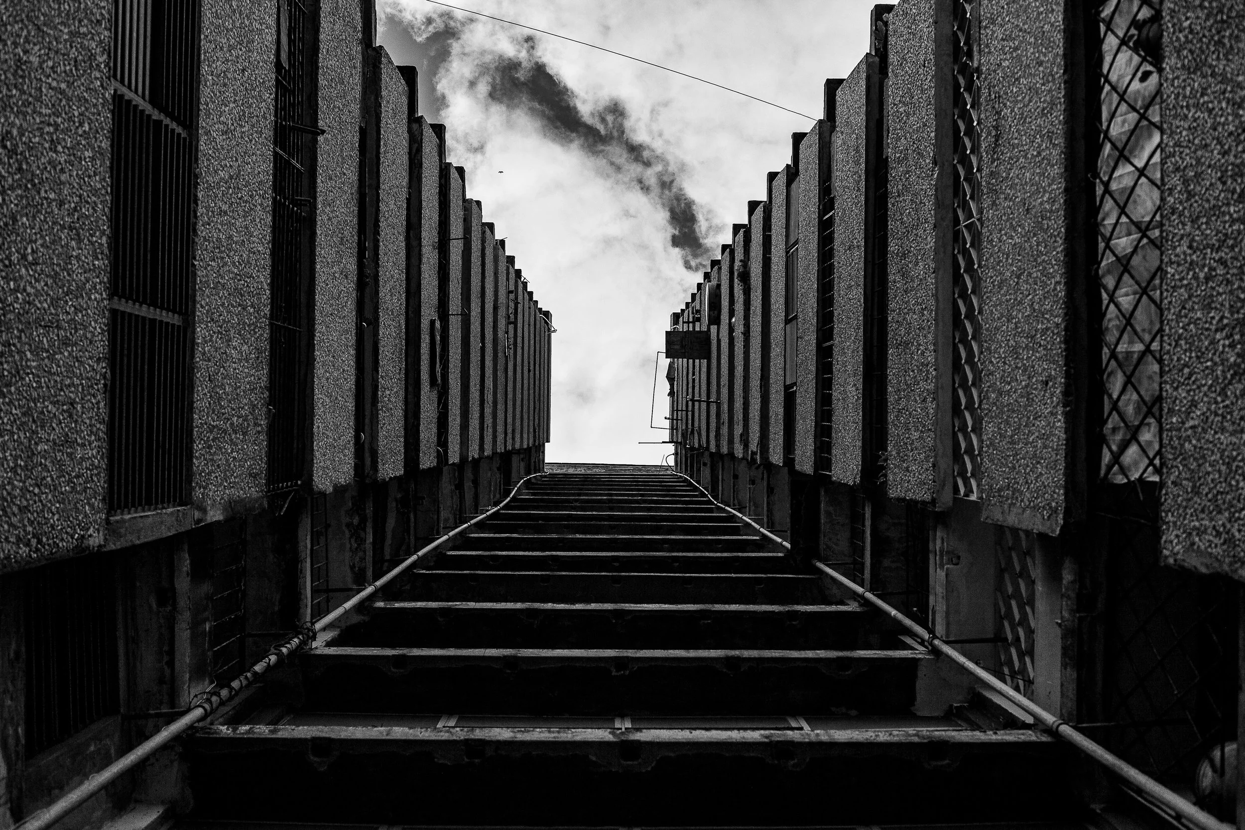 Complete uncropped artwork for Industrial Ascent, showing a steep service stair climbs between repeating industrial walls toward a plume of steam