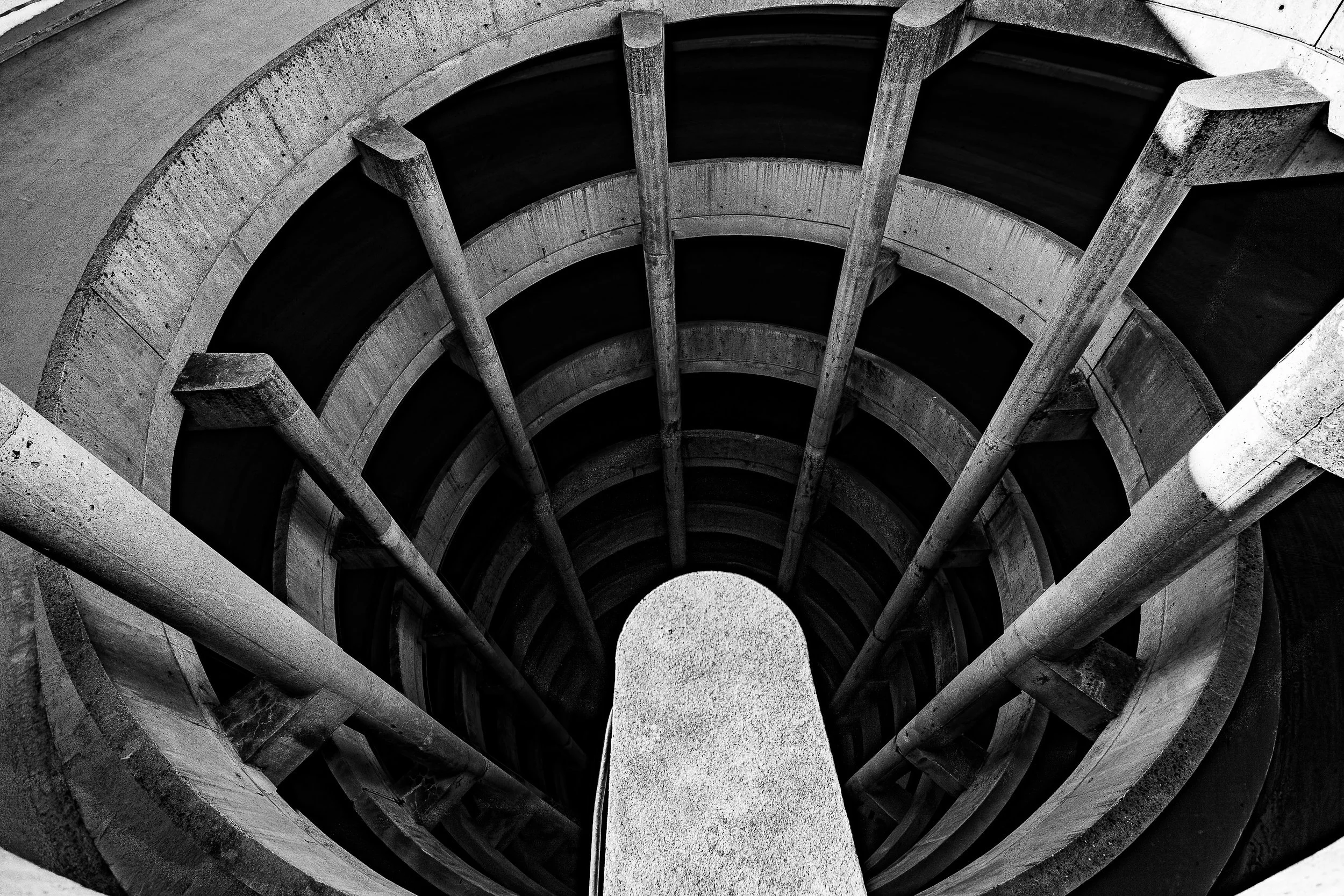 Complete uncropped artwork for Spiral Descent, showing a black-and-white concrete spiral ramp curves around a bright central pier