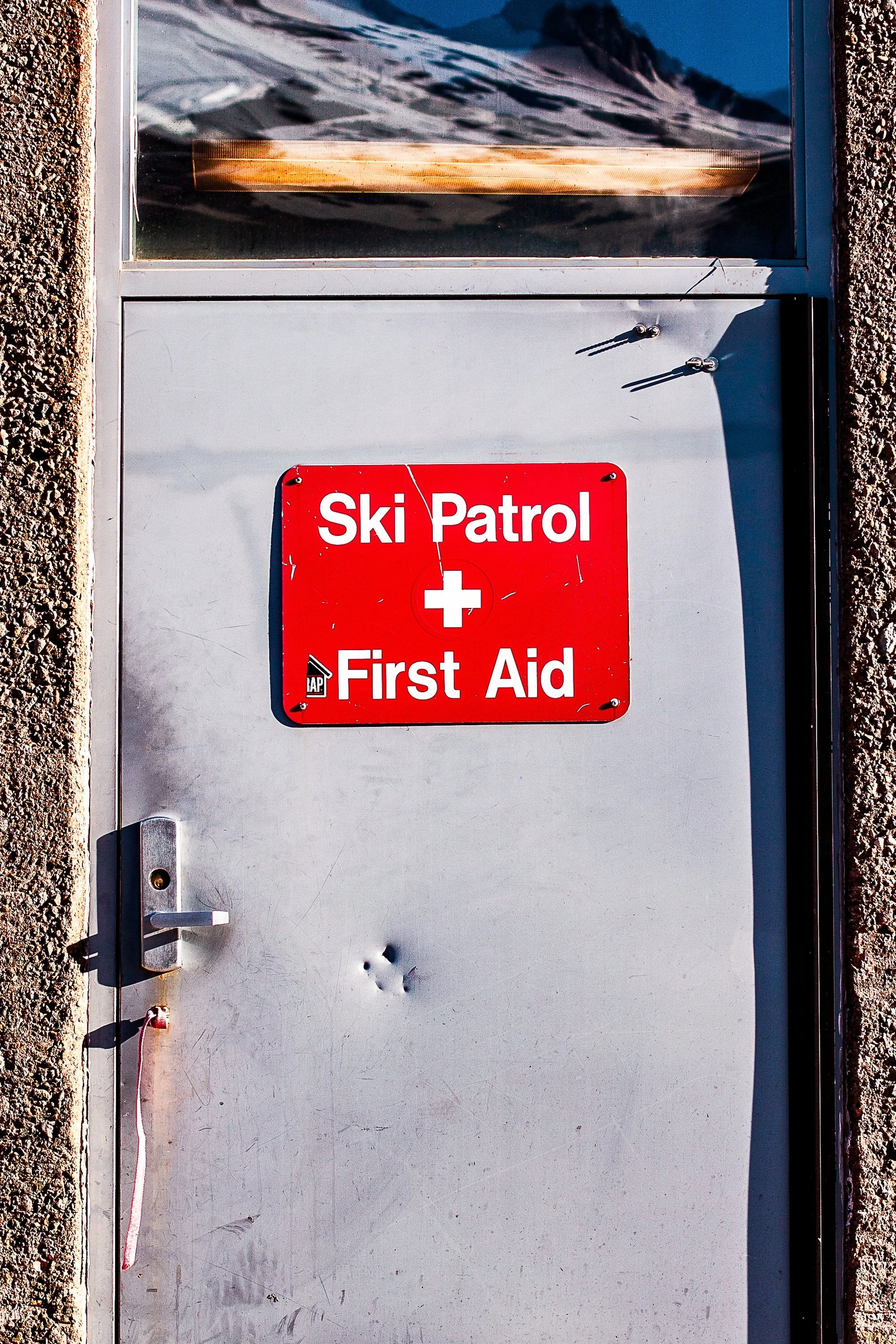 Detail crop from First Aid, emphasizing scratches, hardware, and concrete texture reveal the door's daily use