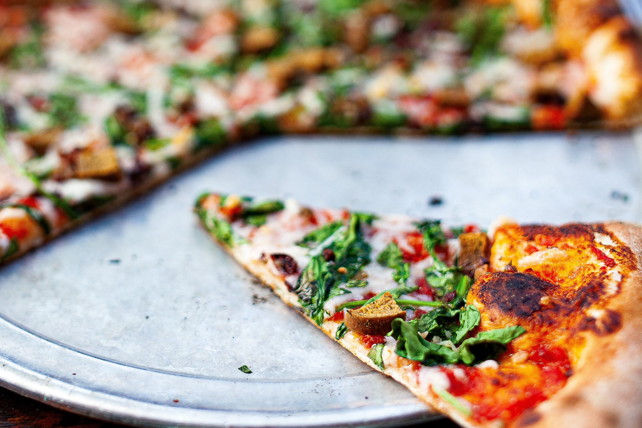 Detail crop from Last Slice, emphasizing toppings, crumbs, and shallow focus keep the casual table scene visually active