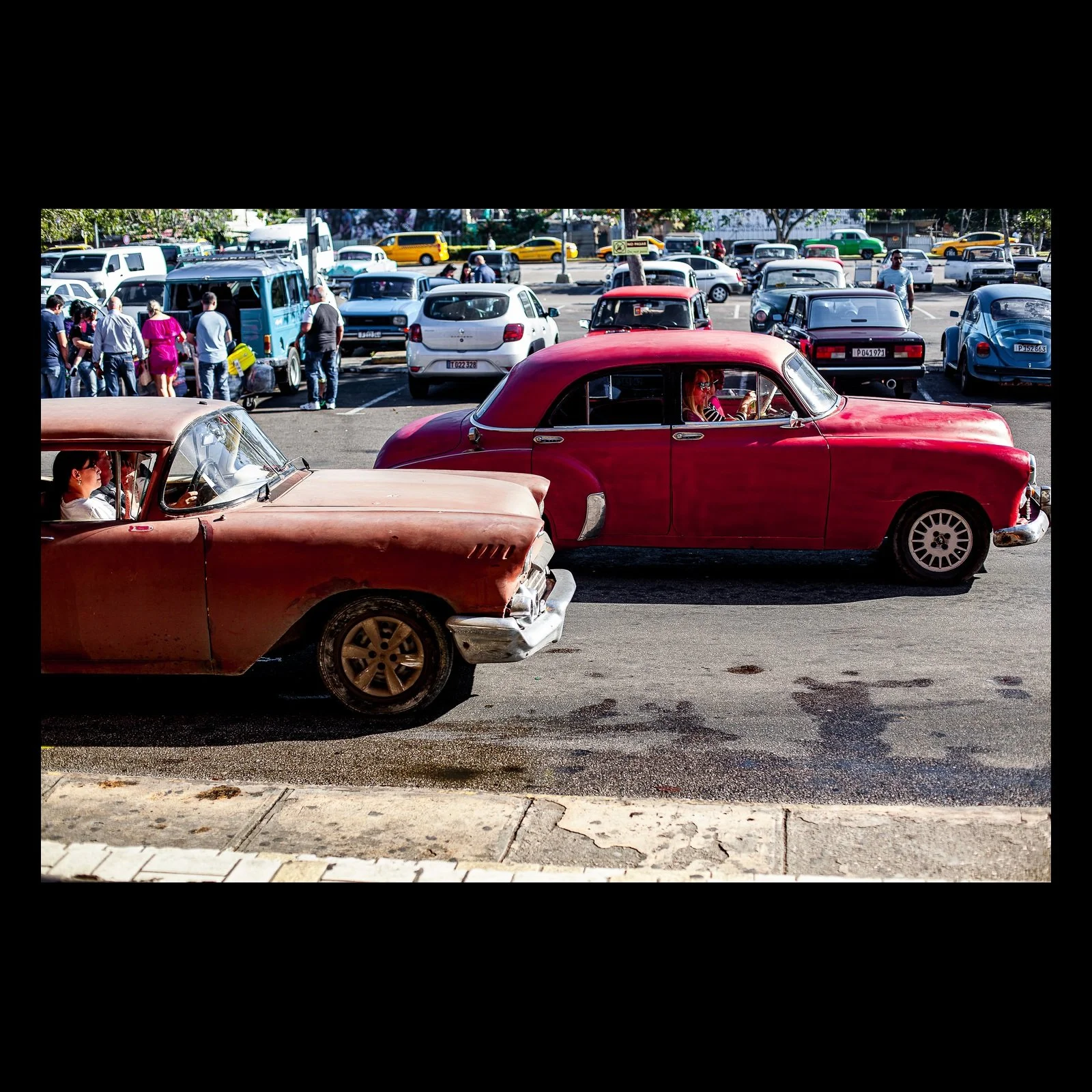 Full-frame black presentation thumbnail of A Step Back in Time, showing two vintage cars cross a busy street in opposing directions amid dense traffic