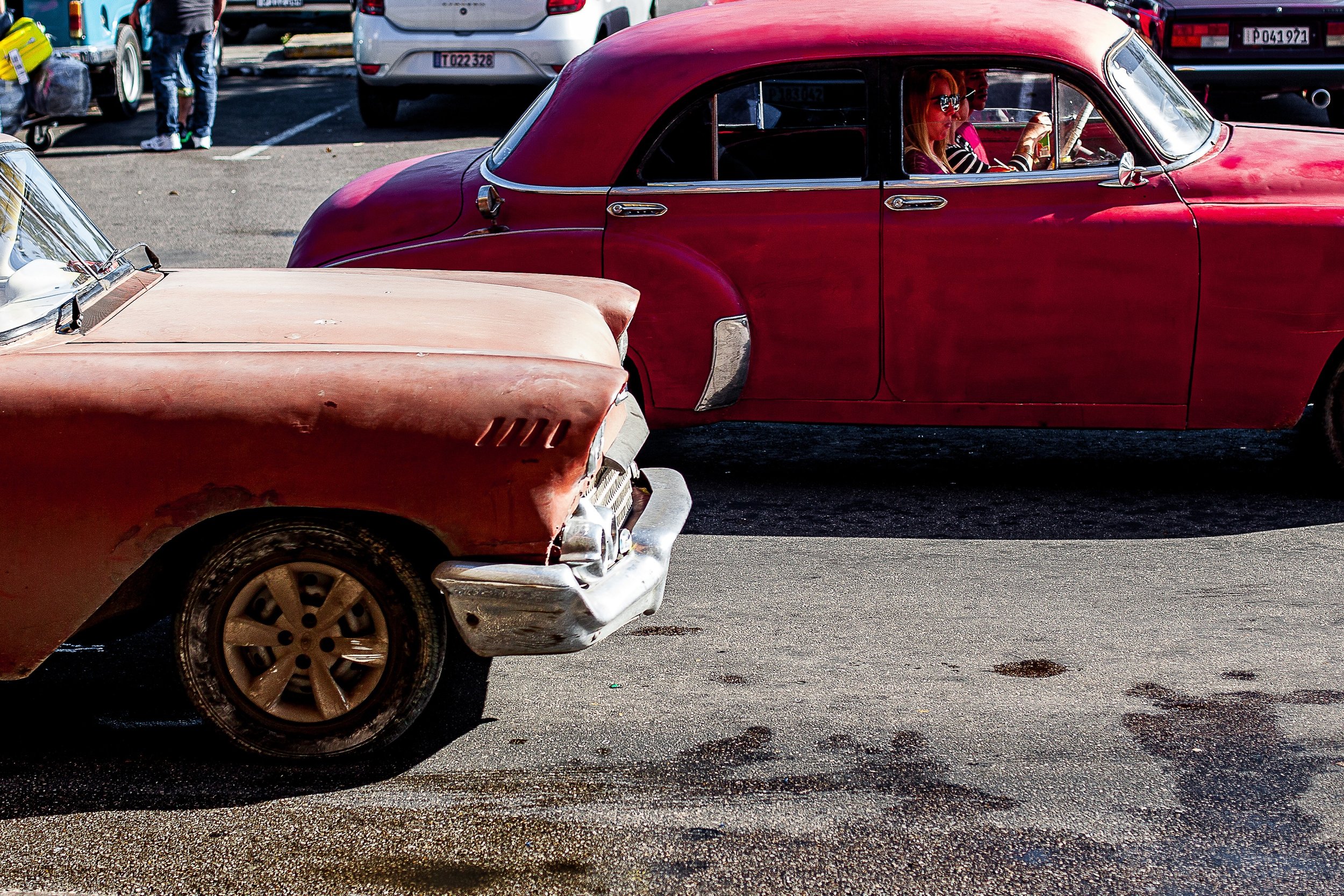 Detail crop from A Step Back in Time, emphasizing drivers, worn paint, and background vehicles reveal several stories at once