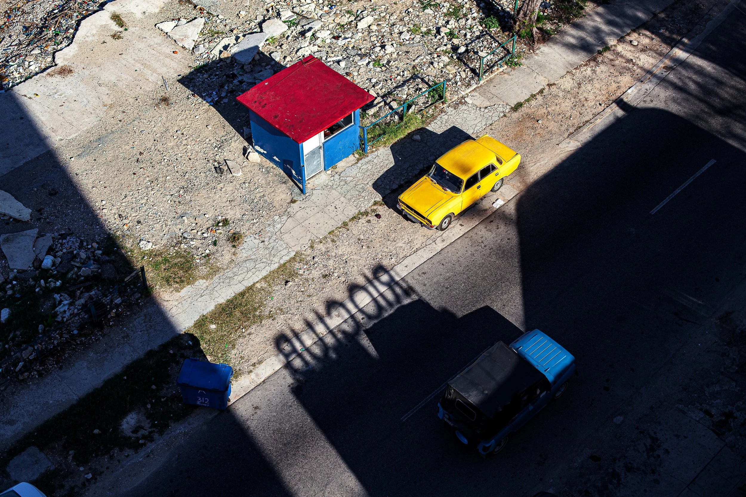 Complete uncropped artwork for Primary Geometry, showing a yellow car and blue-roofed structure sit inside strong blocks of shadow viewed from above