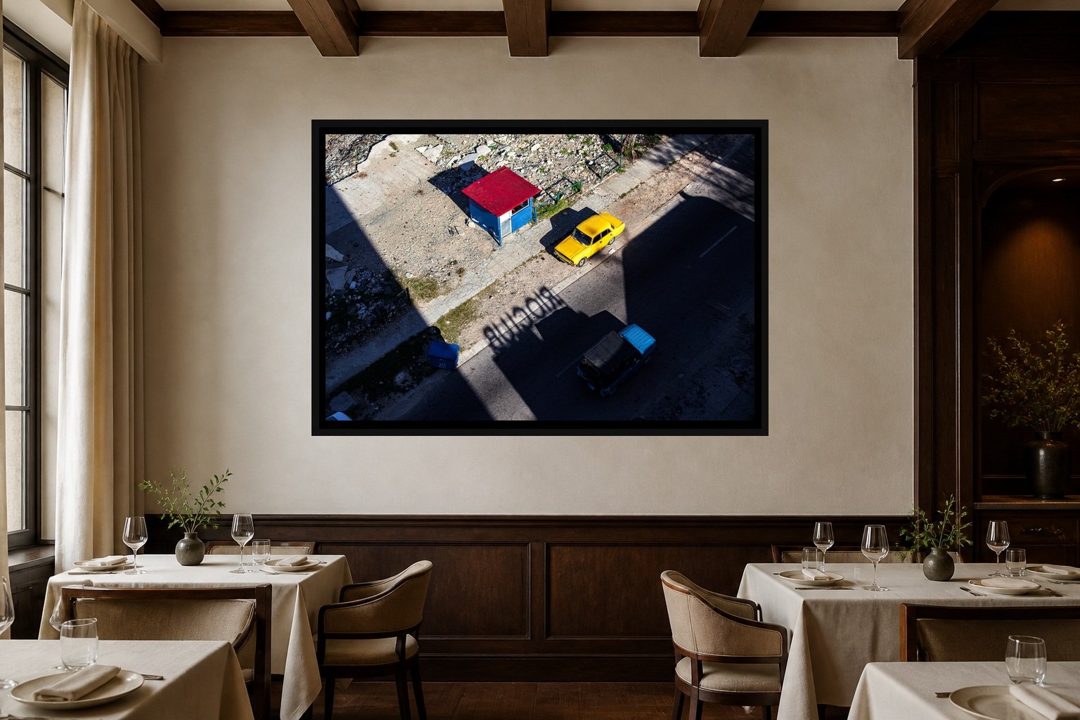 Primary Geometry displayed in a black frame within an intimate fine-dining room with plaster walls, dark wood, linen tables, no guests, and a clear central wall
