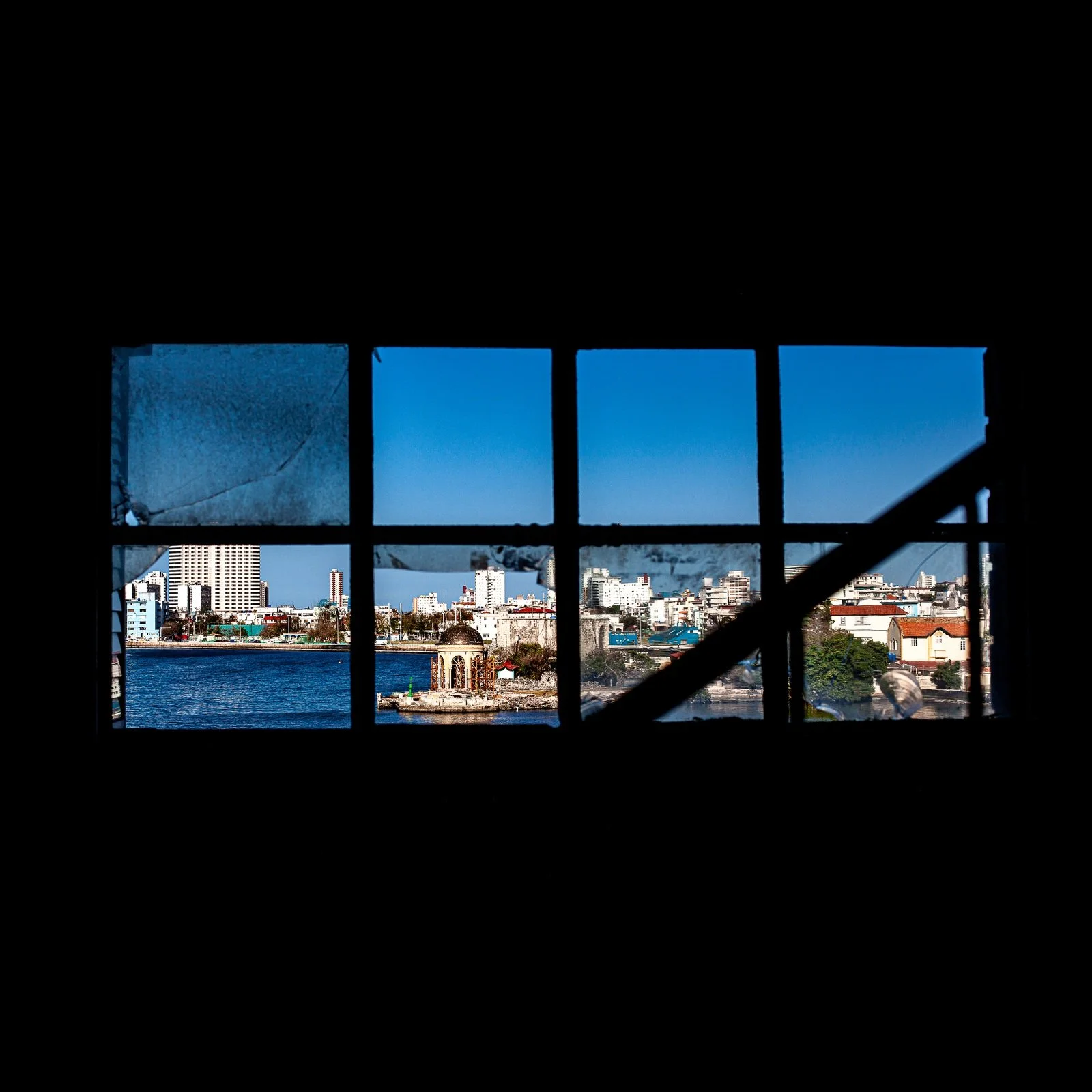 Full-frame black presentation thumbnail of City in Nine Frames, showing a waterfront city is seen through dark industrial window panes and crossing beams