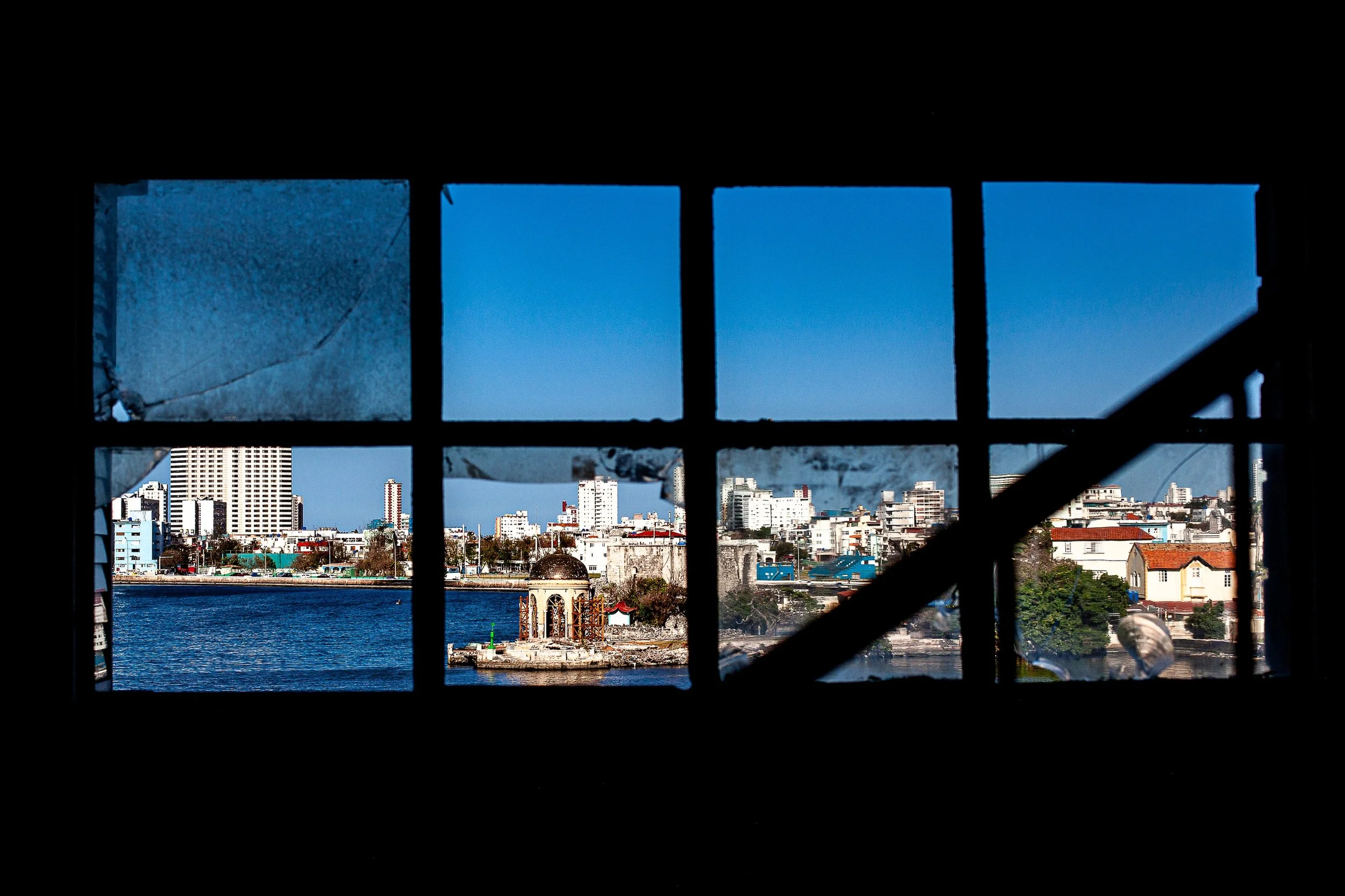 Complete uncropped artwork for City in Nine Frames, showing a waterfront city is seen through dark industrial window panes and crossing beams