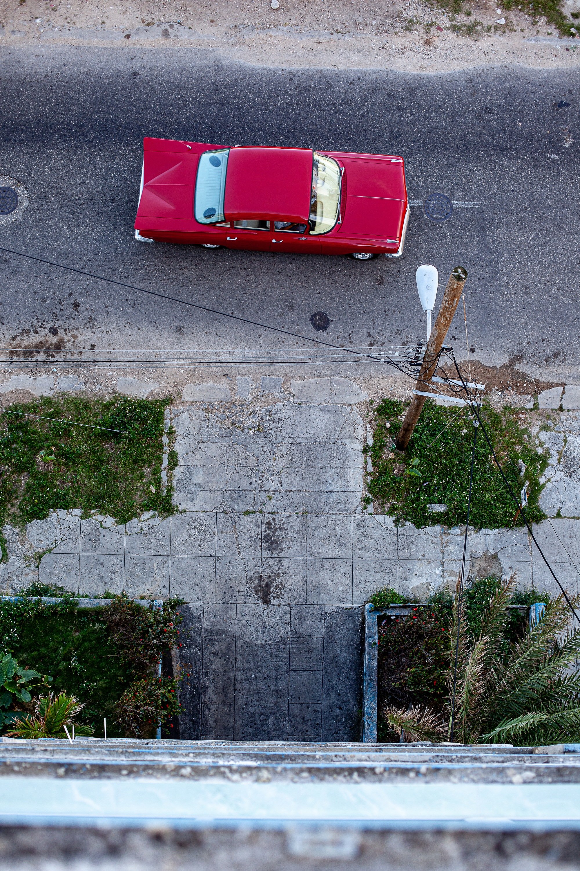 Complete uncropped artwork for 59 Impala, showing a small red car is viewed straight down beside pale pavement and an empty concrete path