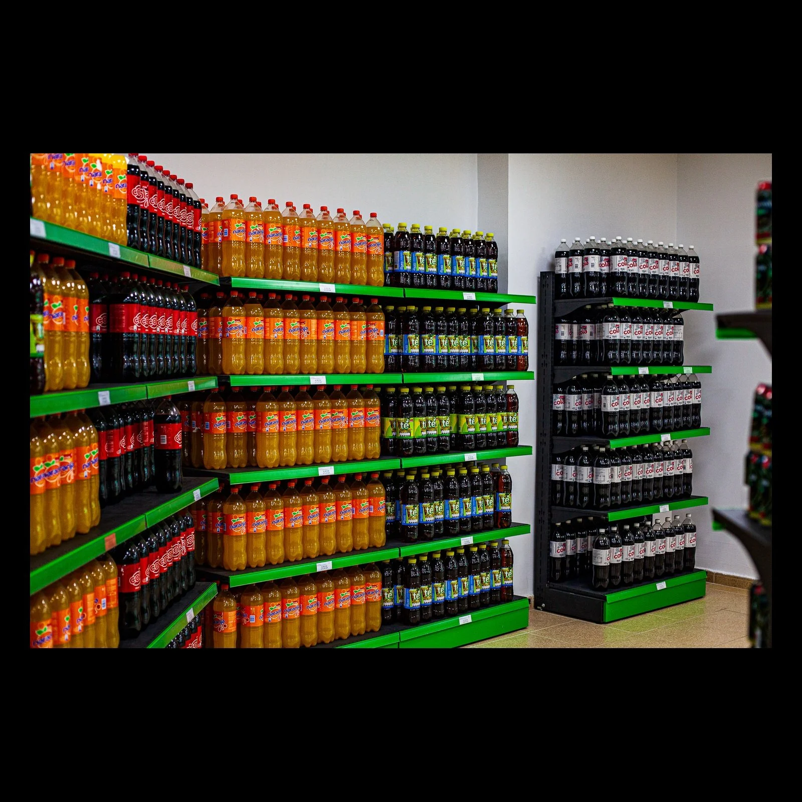 Full-frame black presentation thumbnail of Bottled Color, showing rows of brightly colored bottled drinks fill green retail shelves