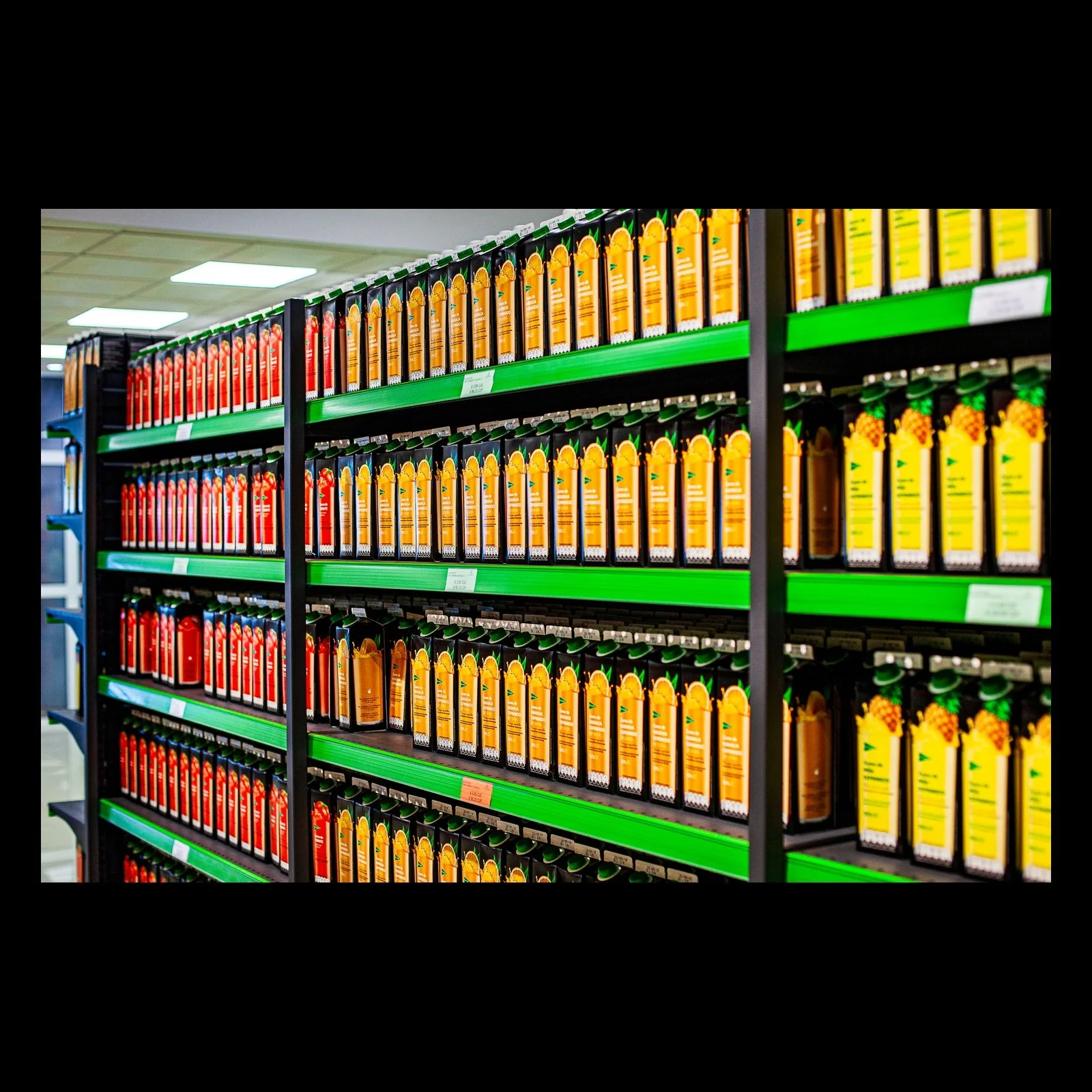 Full-frame black presentation thumbnail of Repetition in Orange, showing long shelves of orange and yellow bottles recede through a brightly lit store