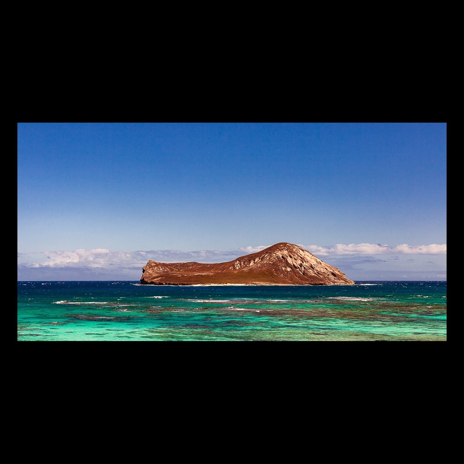 Full-frame black presentation thumbnail of Offshore Red, showing a rust-colored island rises from bands of turquoise and deep blue ocean