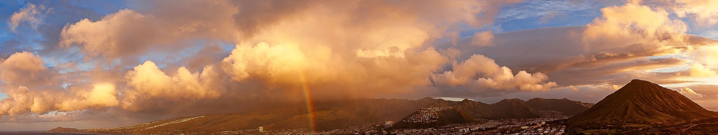 Complete uncropped artwork for Rain Over the Ridge, showing golden clouds and a narrow rain shaft sweep across a dark mountain ridge in a wide panorama