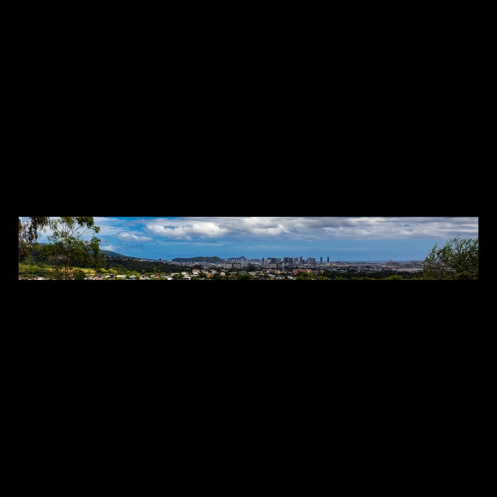 Full-frame black presentation thumbnail of City Beyond the Trees, showing a distant city and coastline appear through a foreground of trees in a narrow panorama