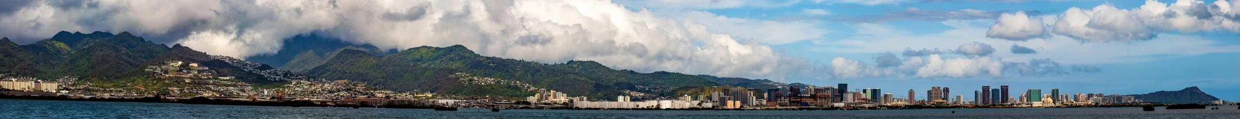 Complete uncropped artwork for Mountain City, showing a long coastal city lies beneath green mountains and heavy white clouds