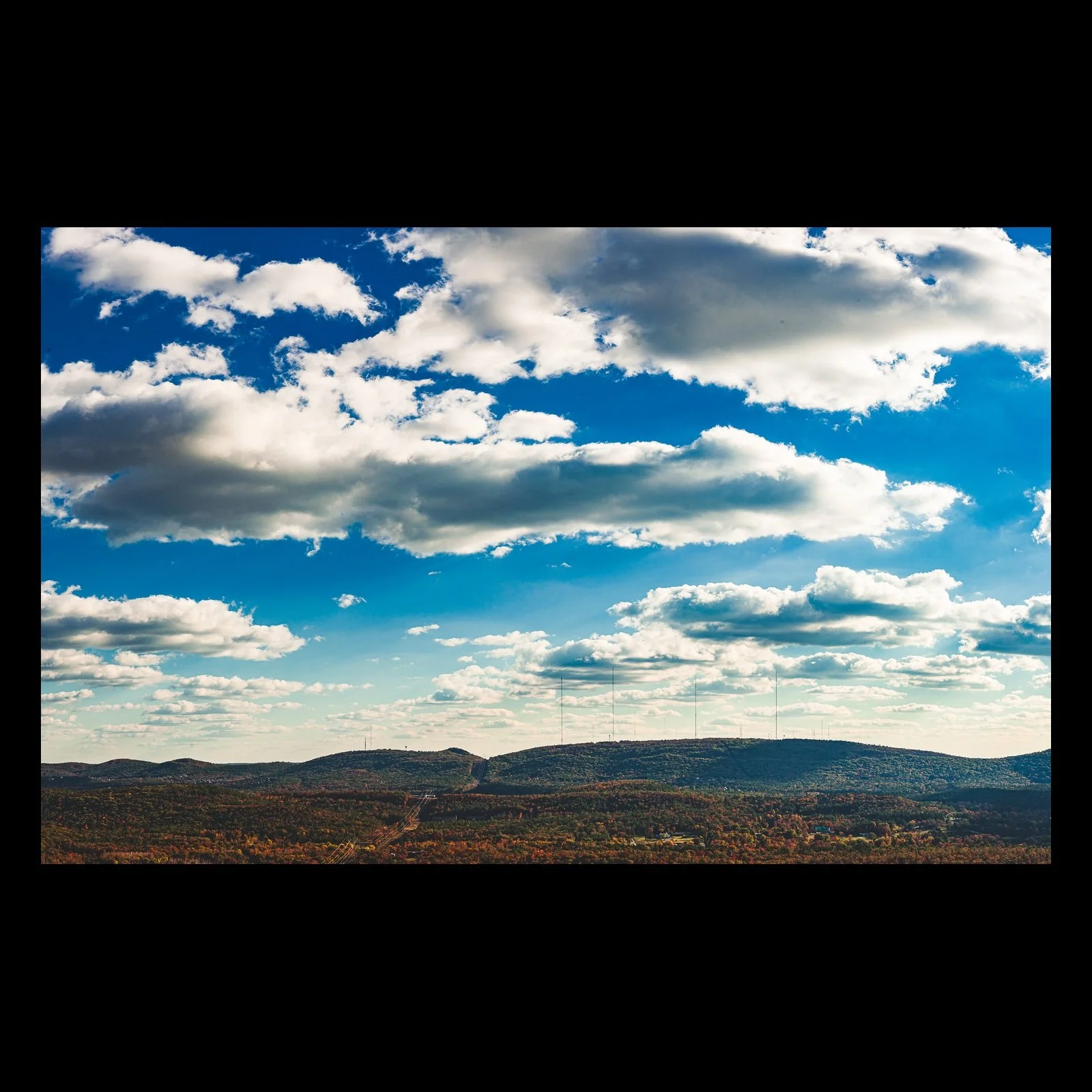 Full-frame black presentation thumbnail of Weather Country, showing large white clouds cast moving shadows across a wide autumn-colored mountain landscape