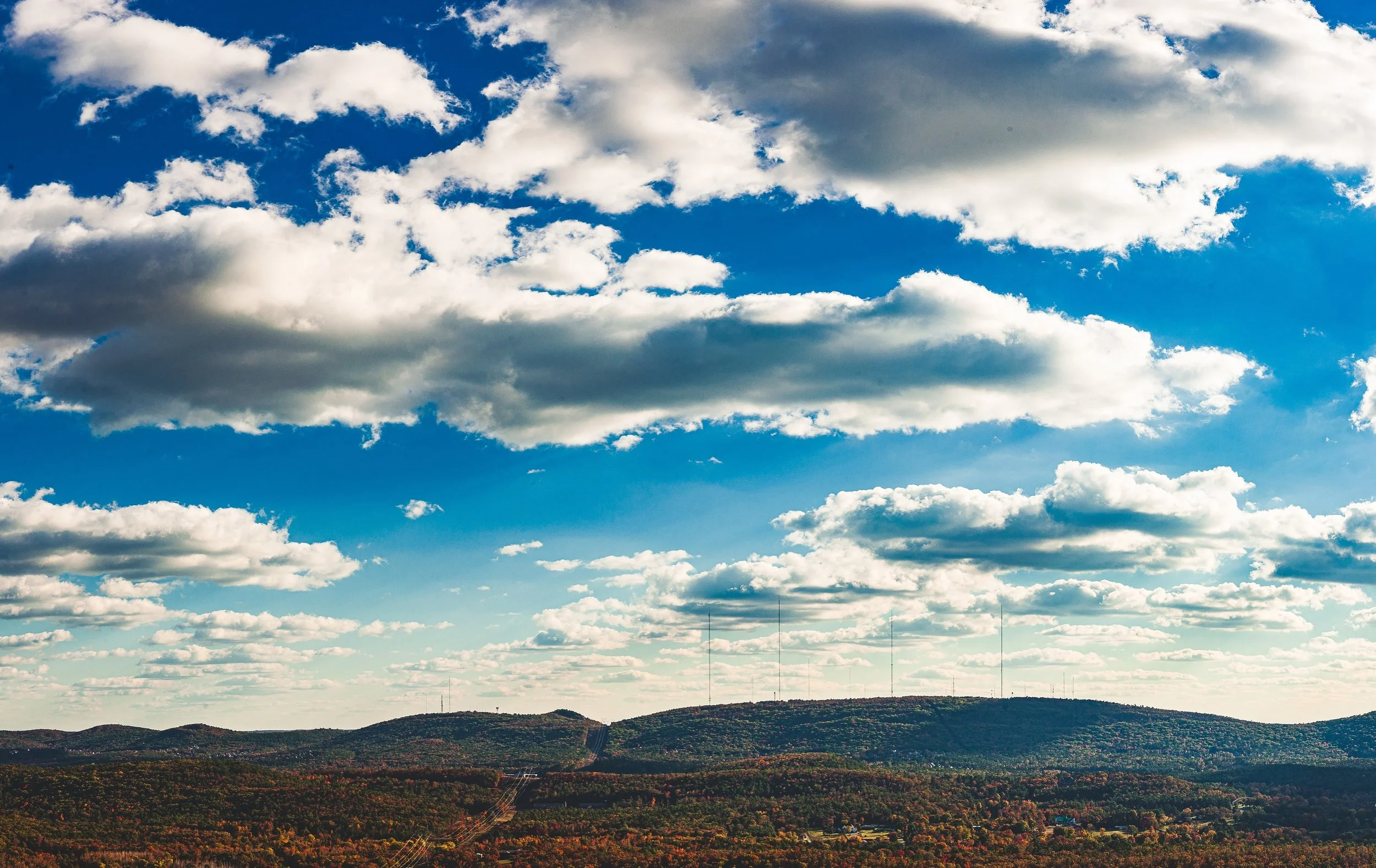 Complete uncropped artwork for Weather Country, showing large white clouds cast moving shadows across a wide autumn-colored mountain landscape