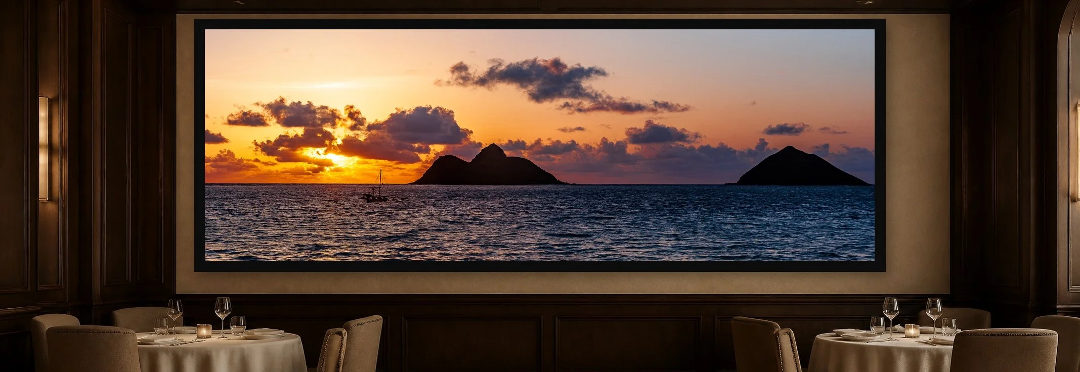 Islands at Sunset displayed in a black frame within an intimate fine-dining room with plaster walls, dark wood, linen tables, no guests, and a clear central wall
