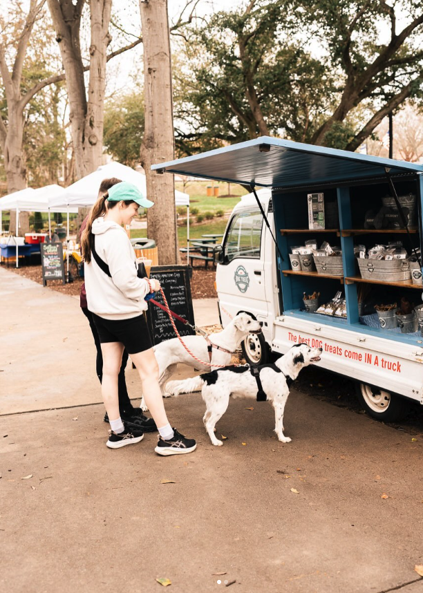 Two dogs visiting the Simply American Dog Treat Truck at a farmer's market in North Carolina