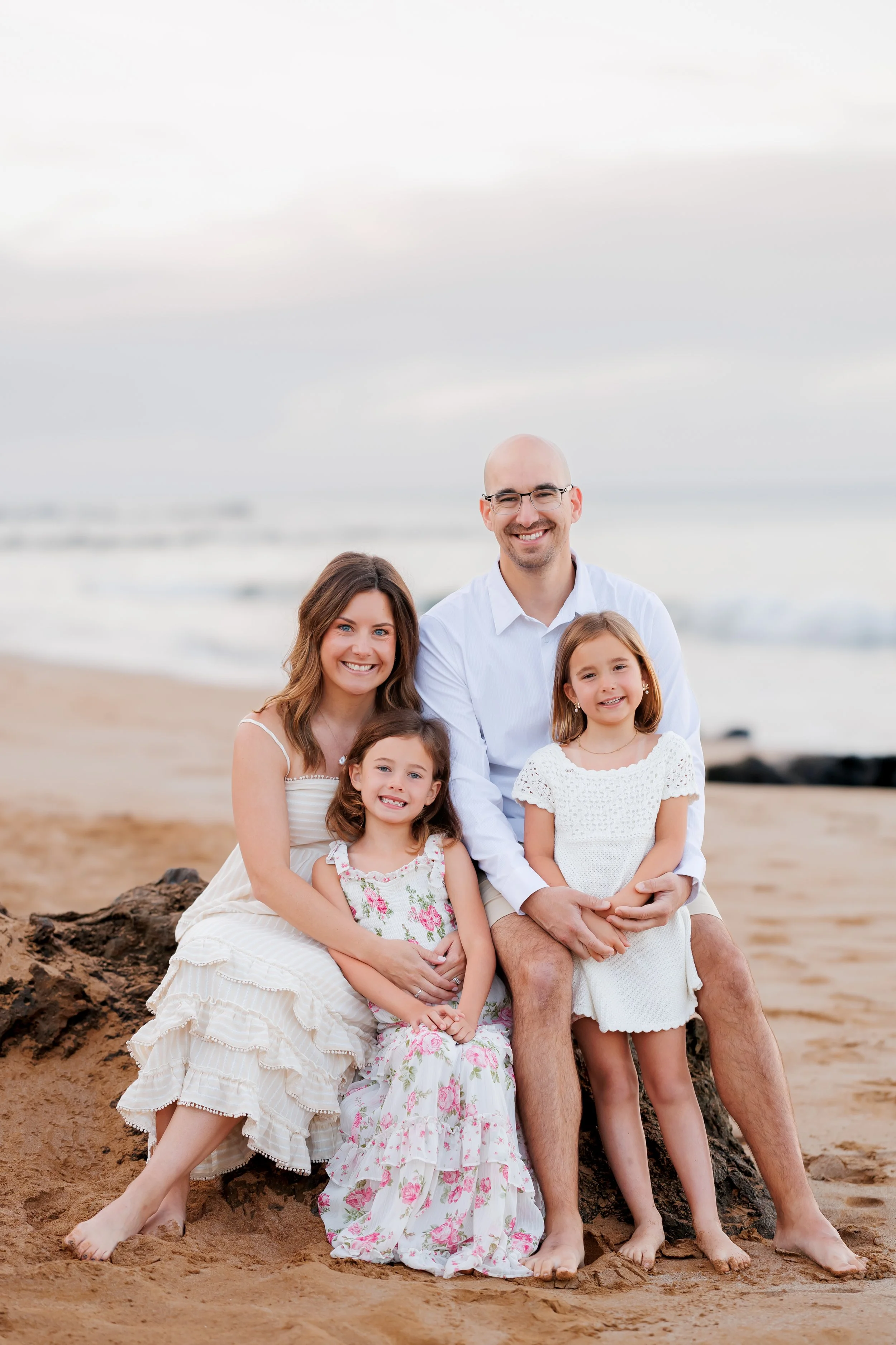 Family snuggling on a lava rock at sunrise in Wailea