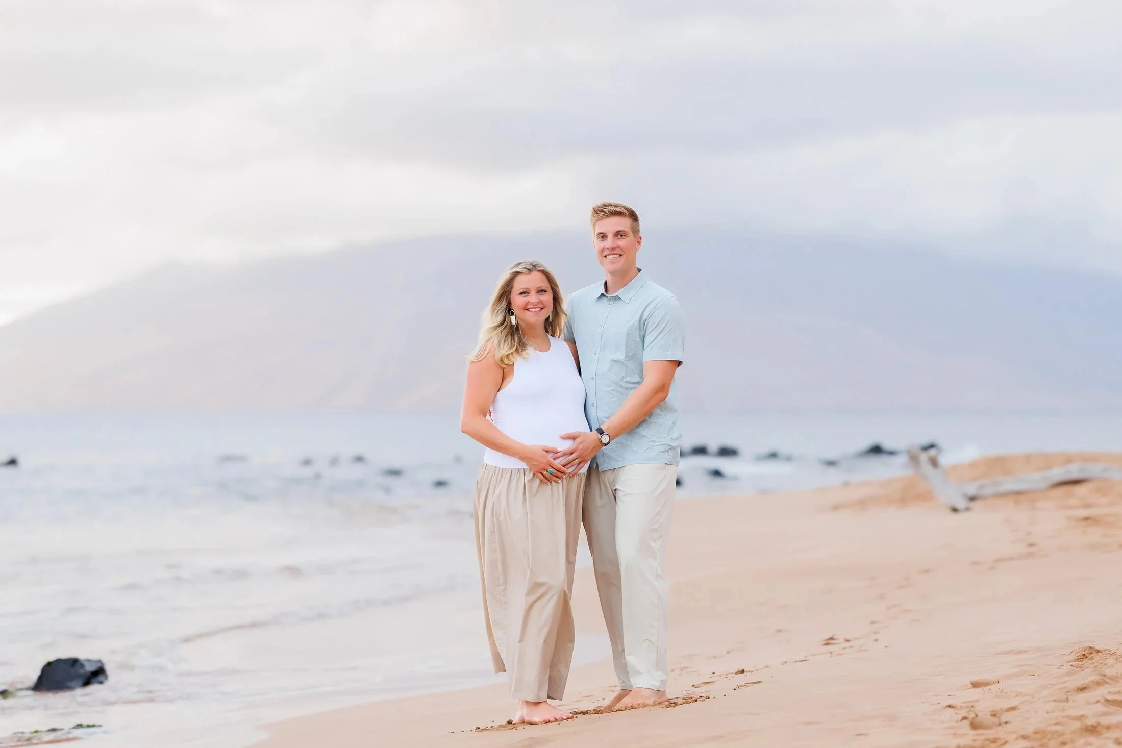 pregnant couple on a babymoon in Maui taking maternity photos on the beach at sunset