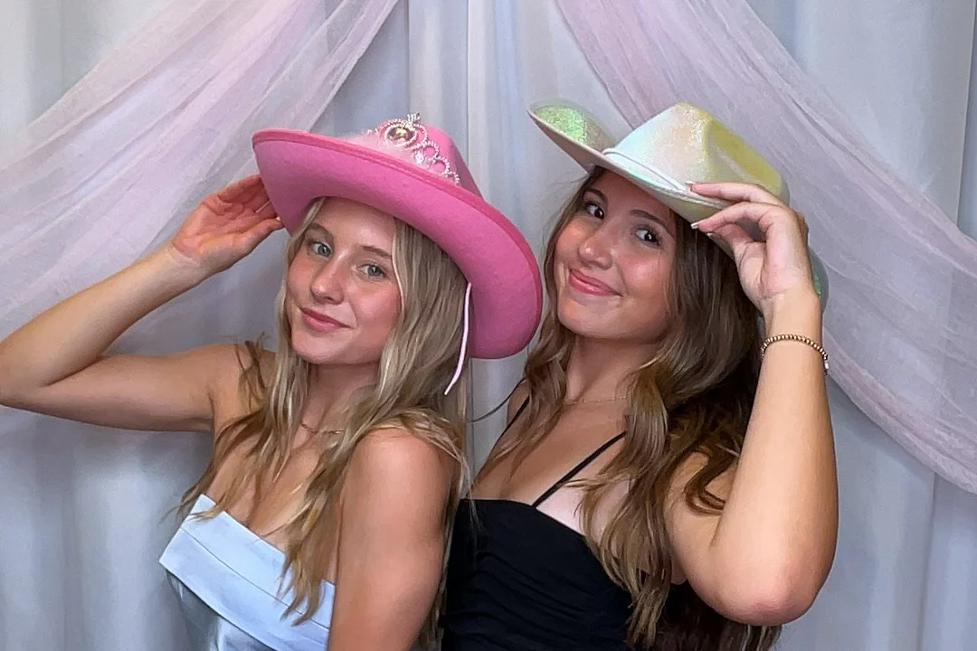 Girls posing in a photobooth with cowboy hats on