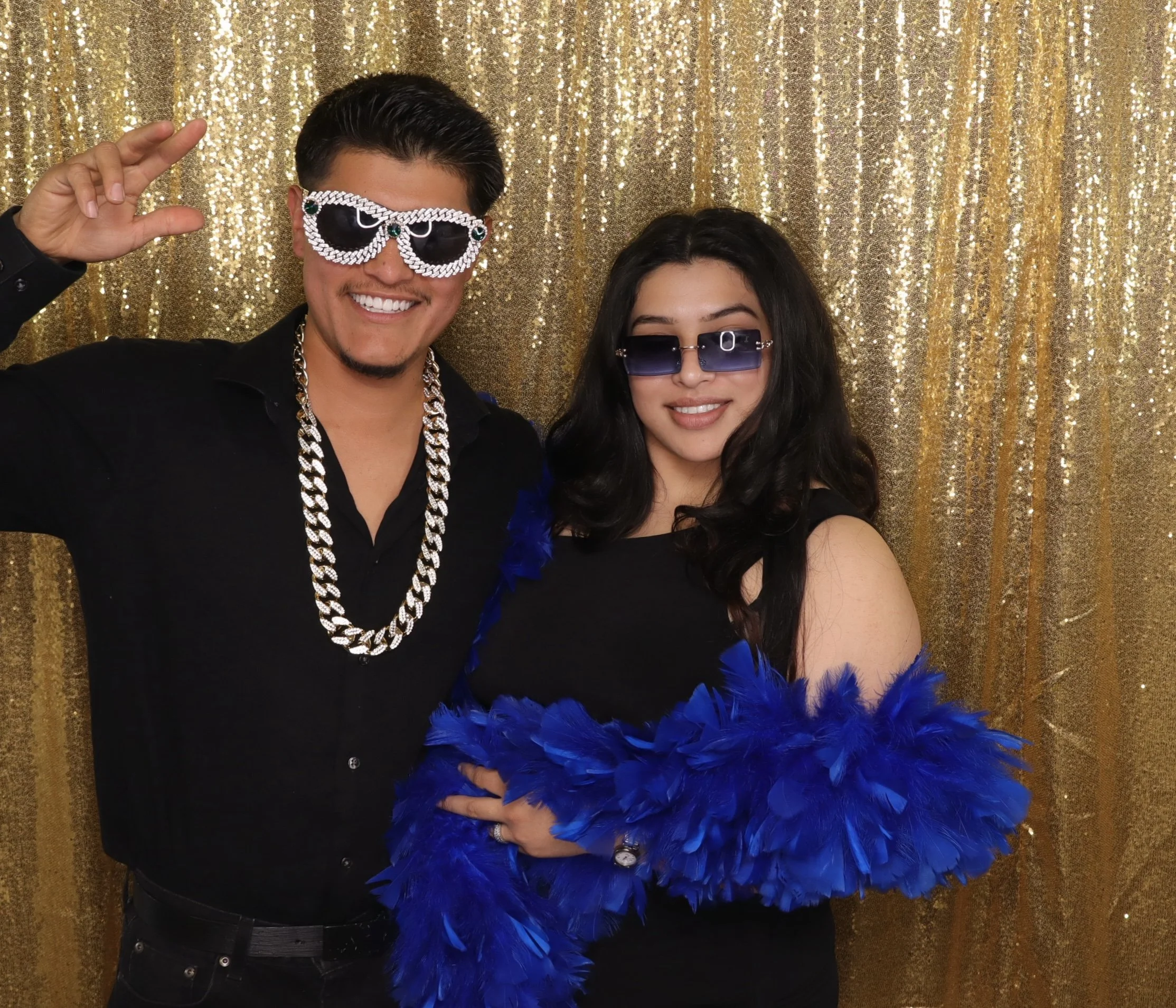 Couple posing with party glasses and blue feather boa 