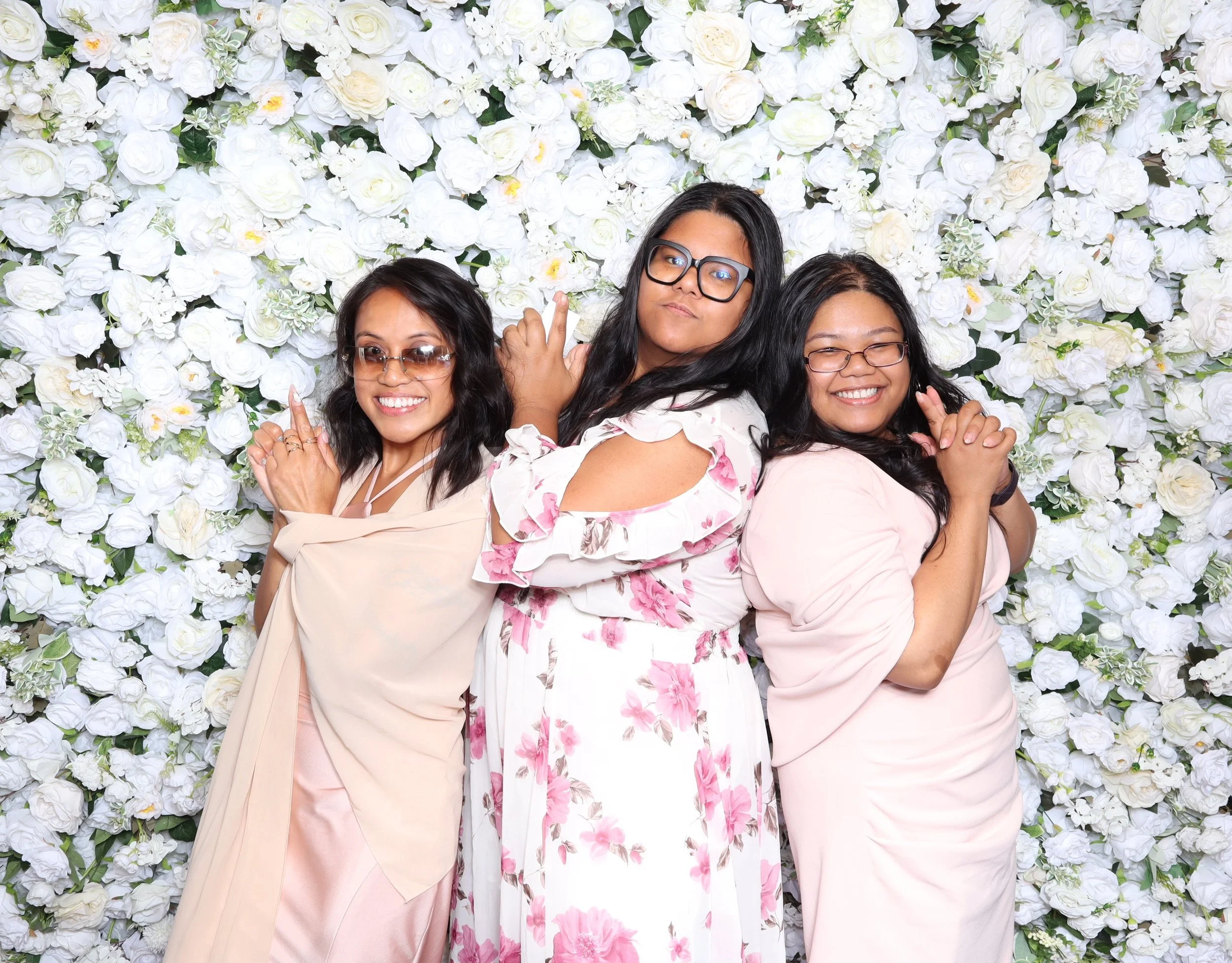 Women Posing Doing the Charlie Angels Pose in front of floral backdrop 