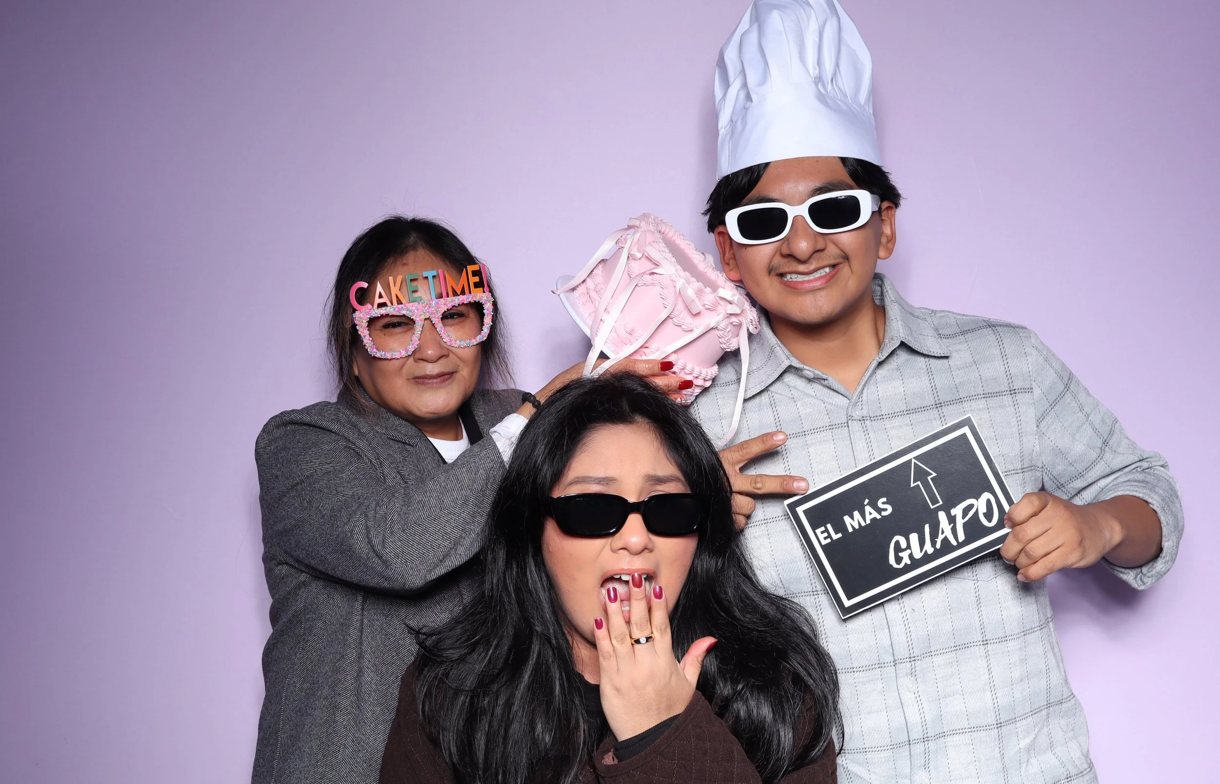 Family posing with prop birthday cake and party glasses 