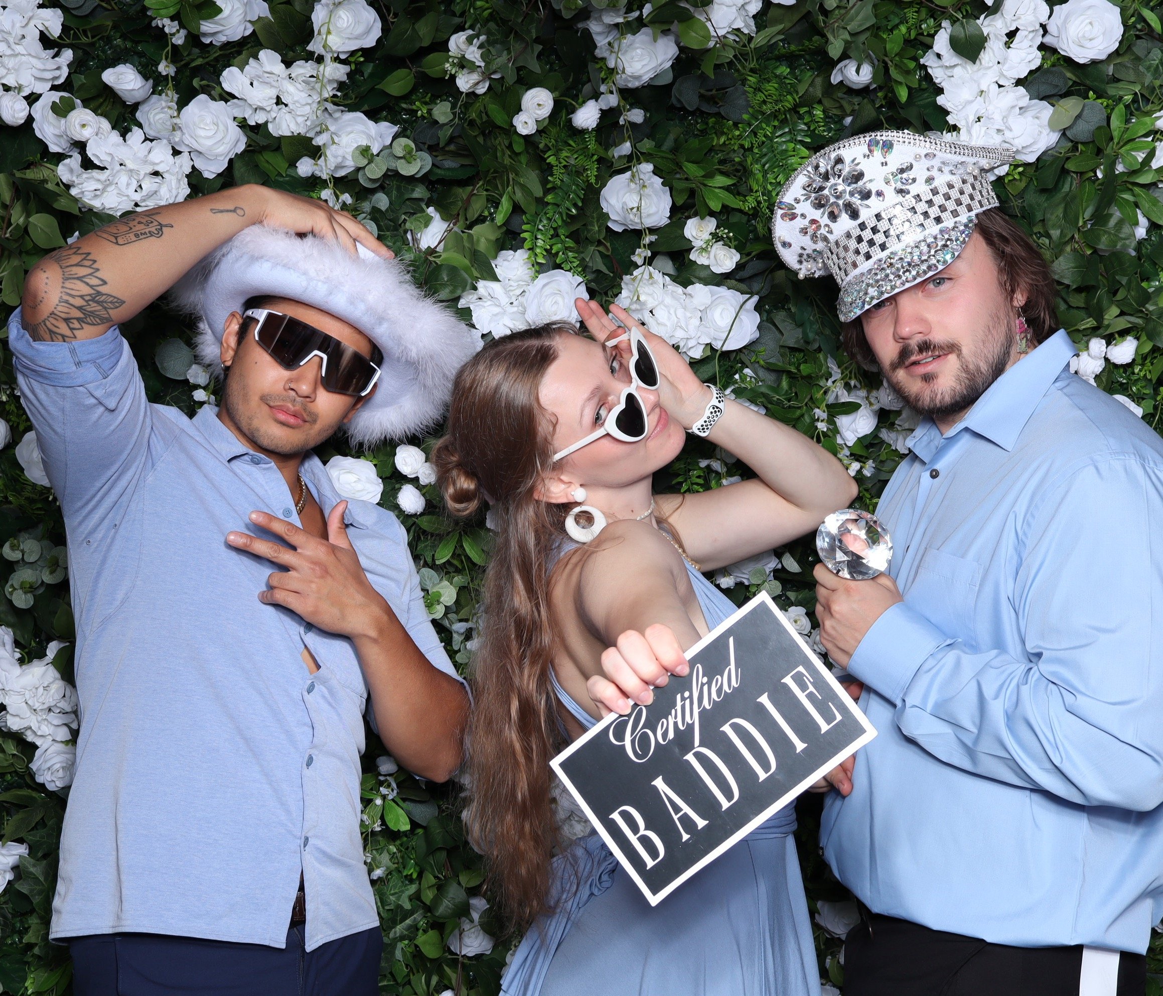 Girl holding psoing with two guys wearing party hats and glasses 