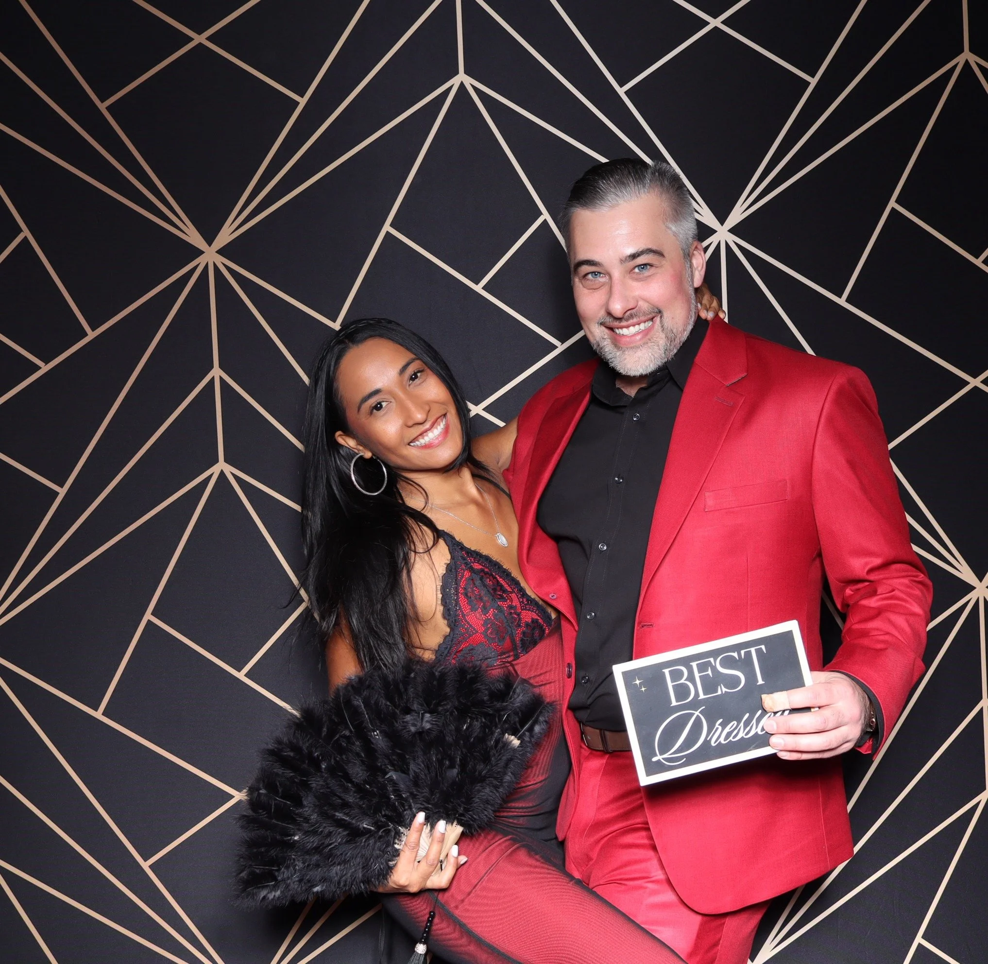 Friends posing with a sign " best dresses" and black feather fan