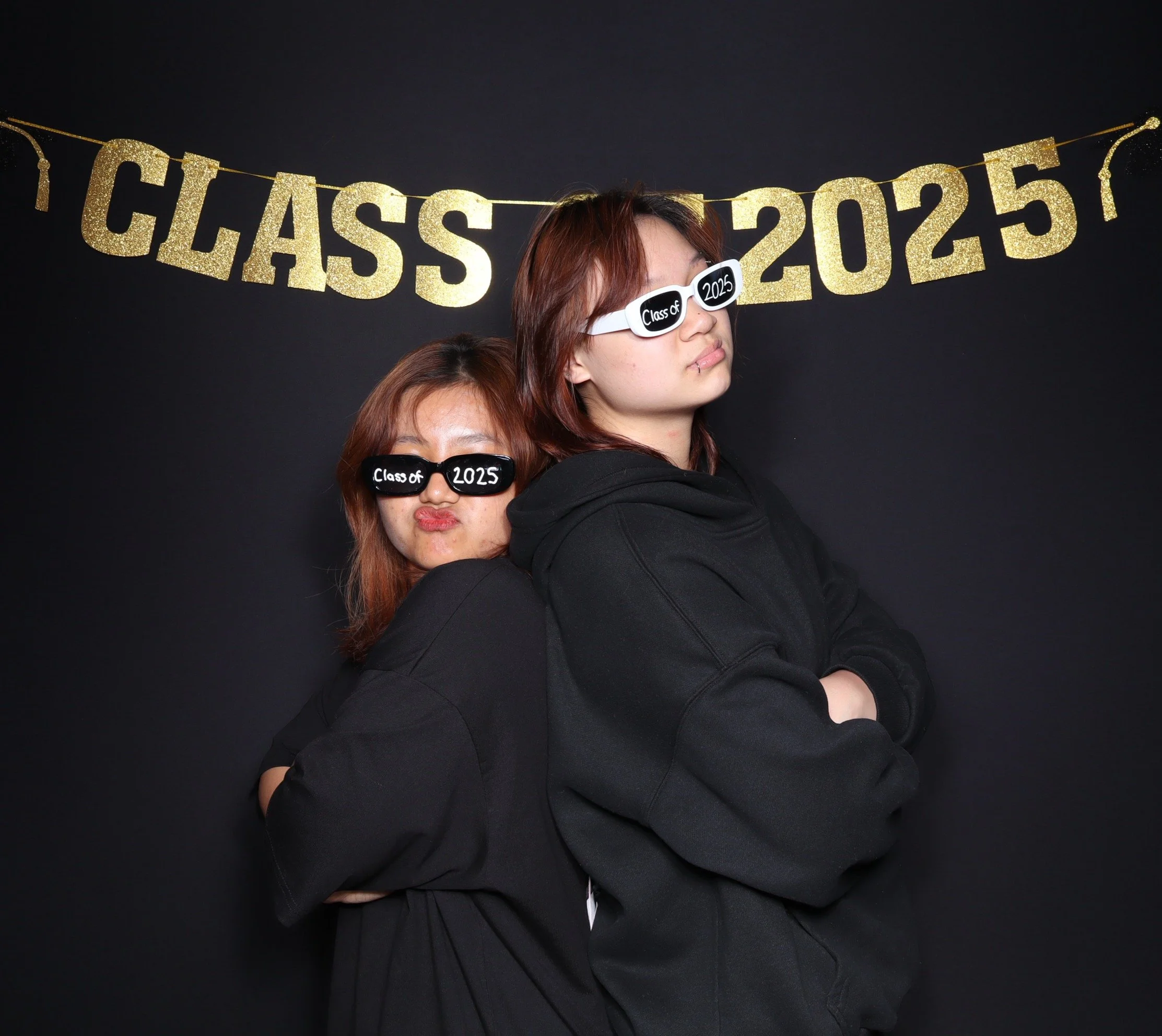 Fiends posing in front of a class of 2025 graduation 