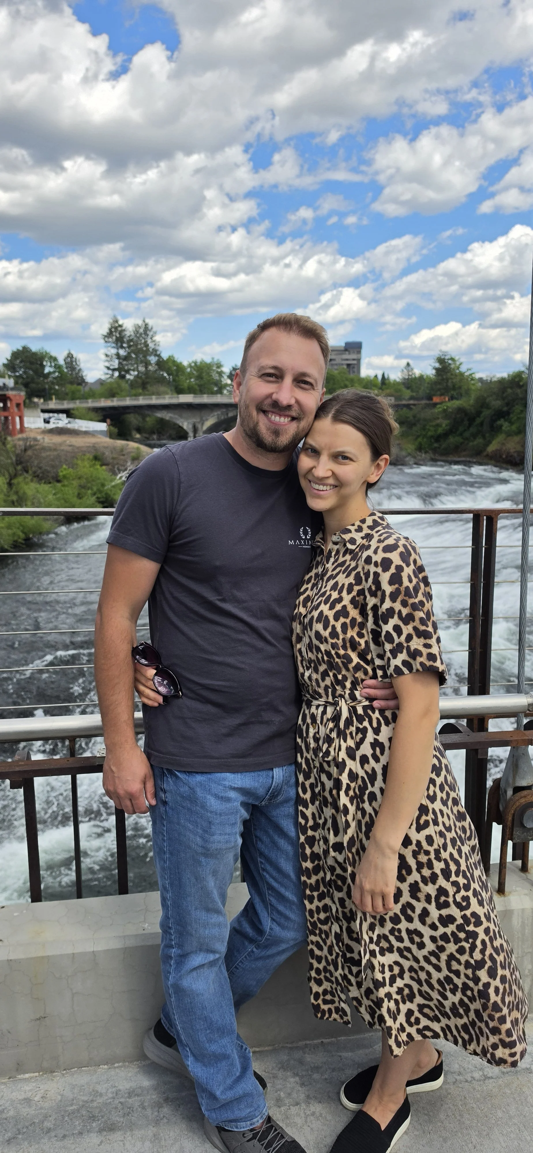 A handsome man who is a builder is standing with a woman.  He builds the best homes in the Spokane area.  Everybody wants to hire him as a builder because his custom home construction company is the best in Spokane, WA.  Best custom home builder