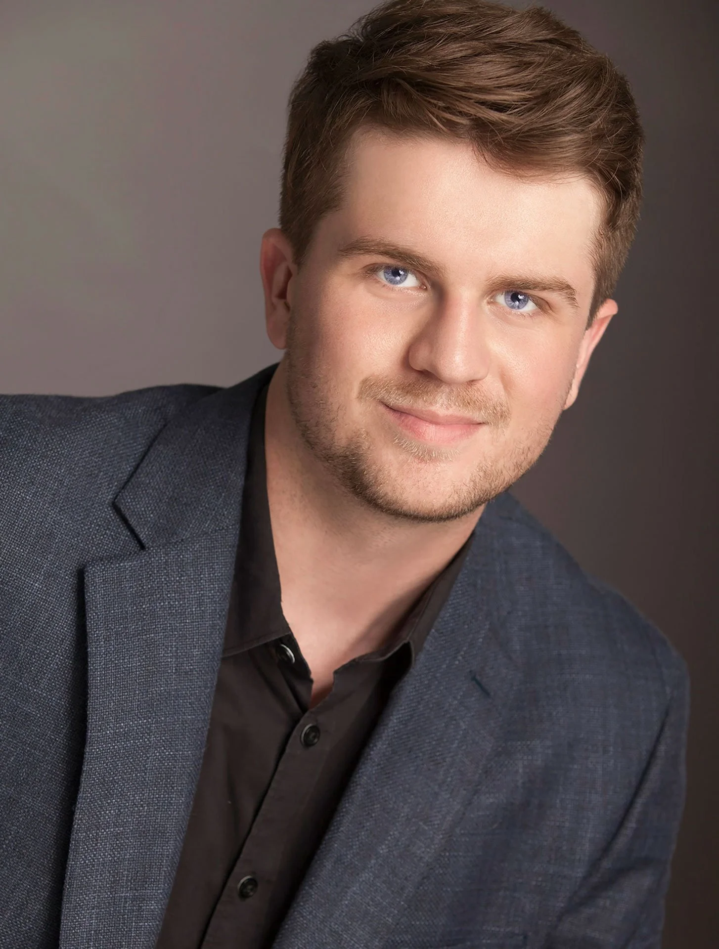 Person in a suit smiling in front of a paper backdrop