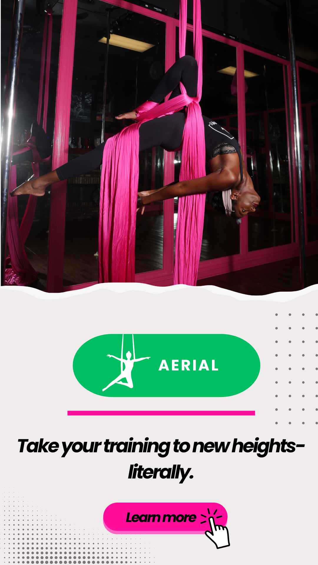 A woman practicing aerial yoga with pink silk hammocks in a studio, hanging upside down in a pose.