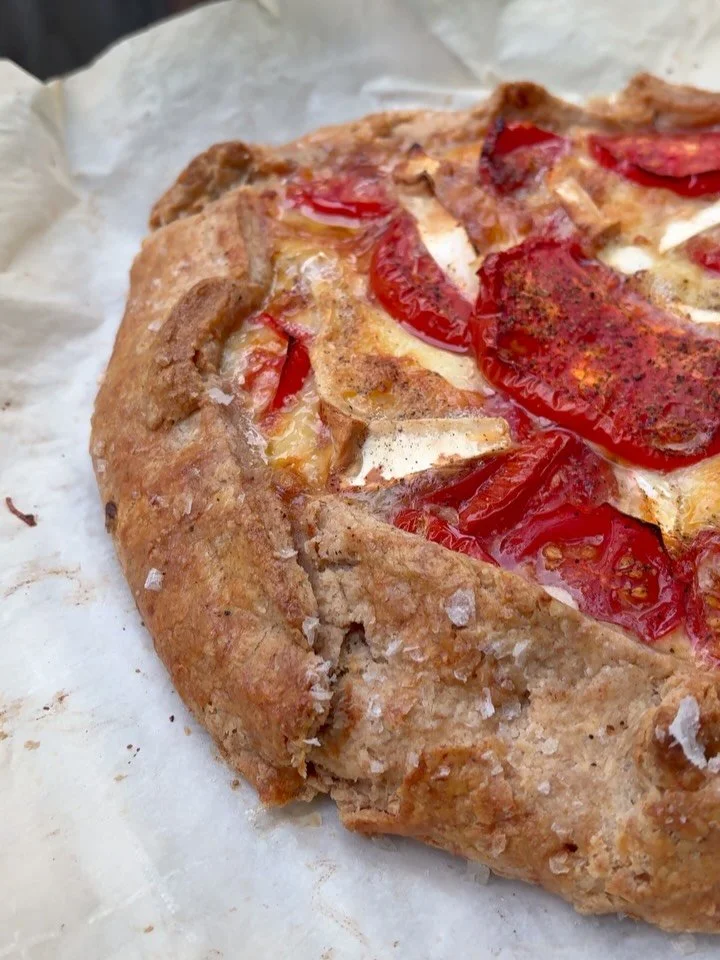 tomato galette with a red wheat crust, sweet onions, and all the left over cheese bits from my fridge, including some perfectly ripe St. Angel. 

The tomatoes were a gift from a good friend. I love this time of year, all the talented gardeners (not m