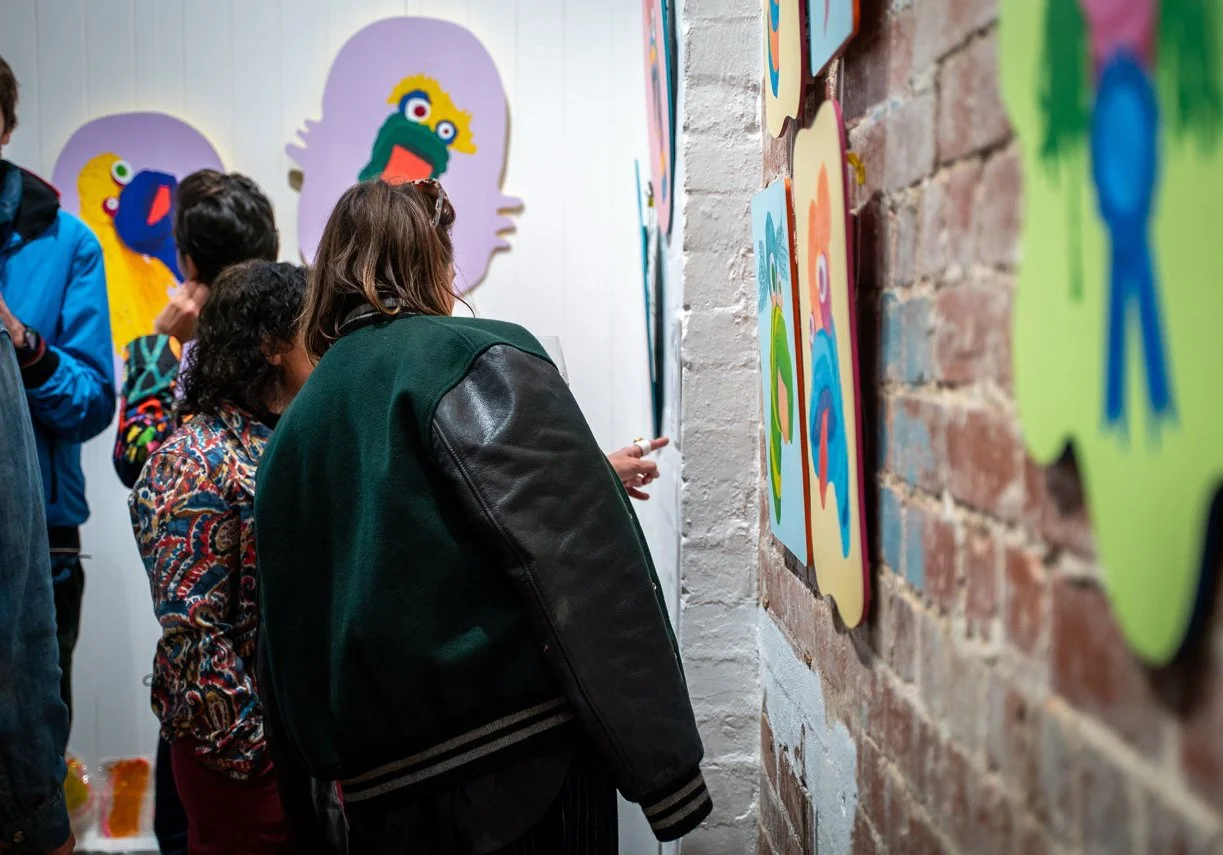 People looking at sock puppet paintings in a gallery