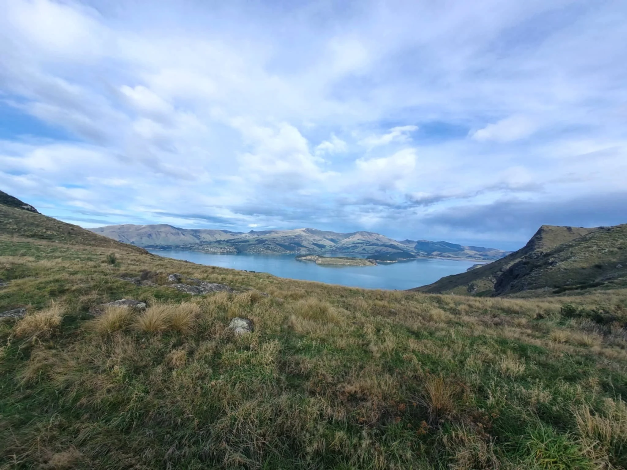 Scenic view of a lake surrounded by hills and mountains under partly cloudy sky