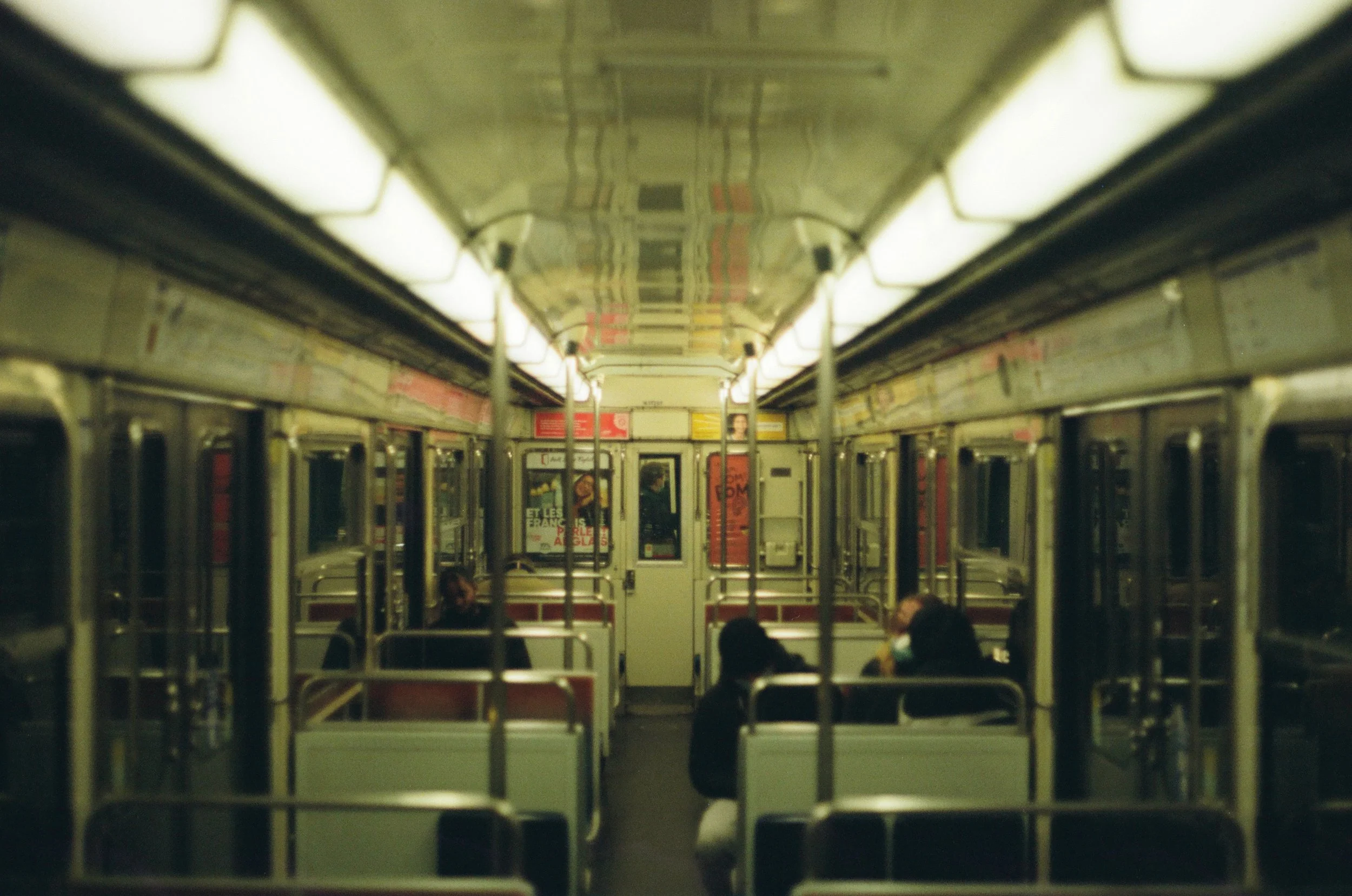 Leeg metro interieur met enkele passagiers en posters aan de muur.