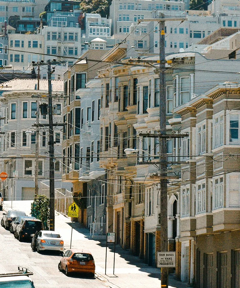Straat met geparkeerde auto's, gekleurde en historische gebouwen, houten telefoonkabels en straatverlichting in San Francisco