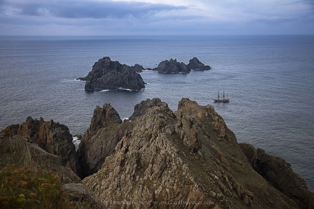 Velero de dos mástiles cruzando entre las formaciones rocosas  características del Cabo Ortegal.