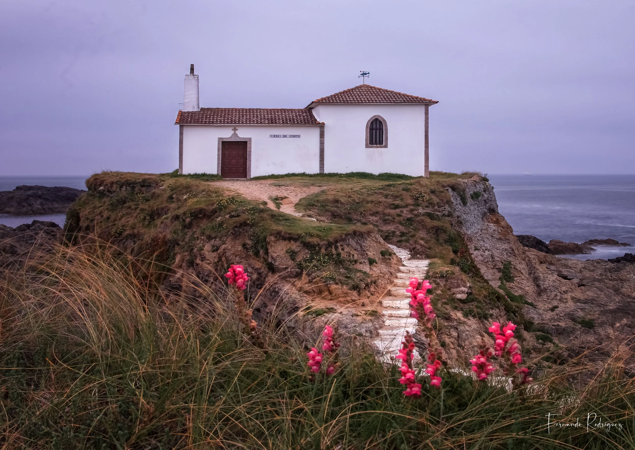 Vista de la Ermita da Virxe do Porto en un día gris, con la vegetación colindante