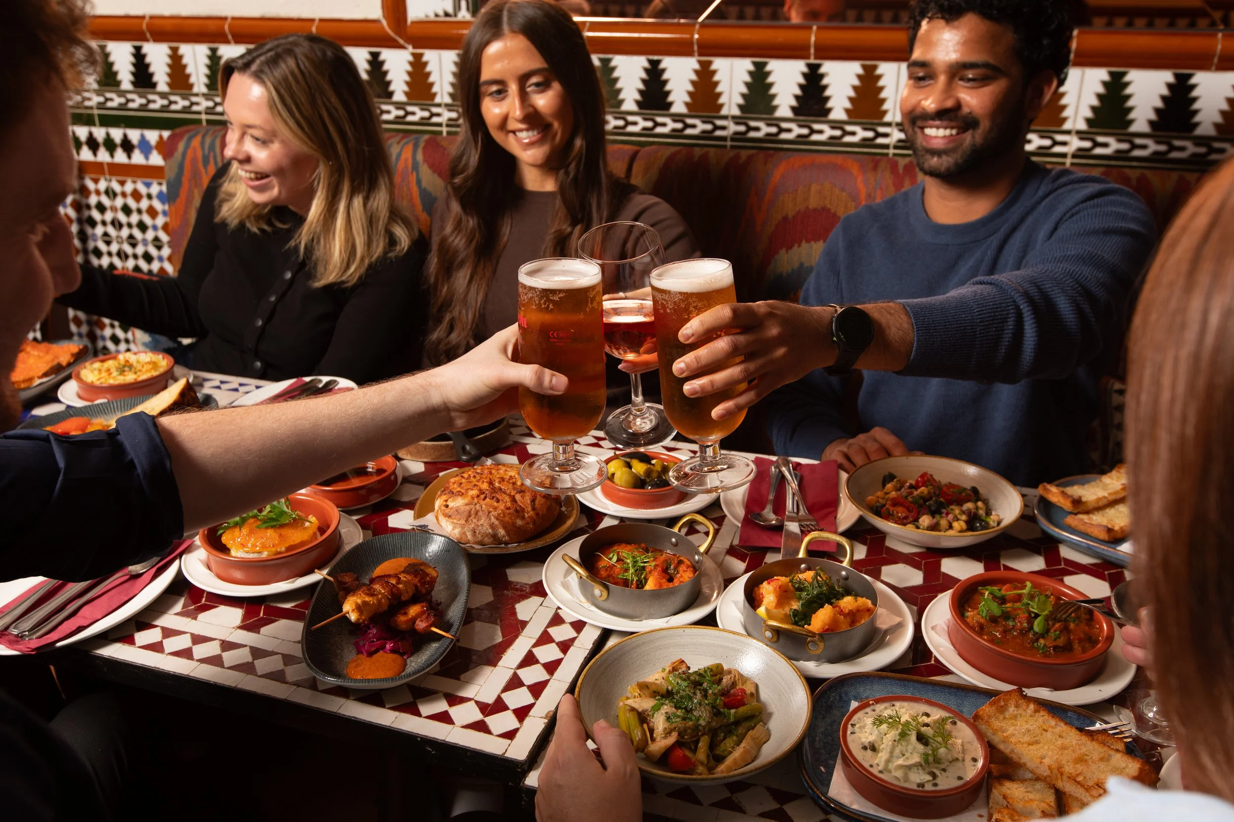 Group of friends enjoying and sharing tapas around a Cafe Andaluz table