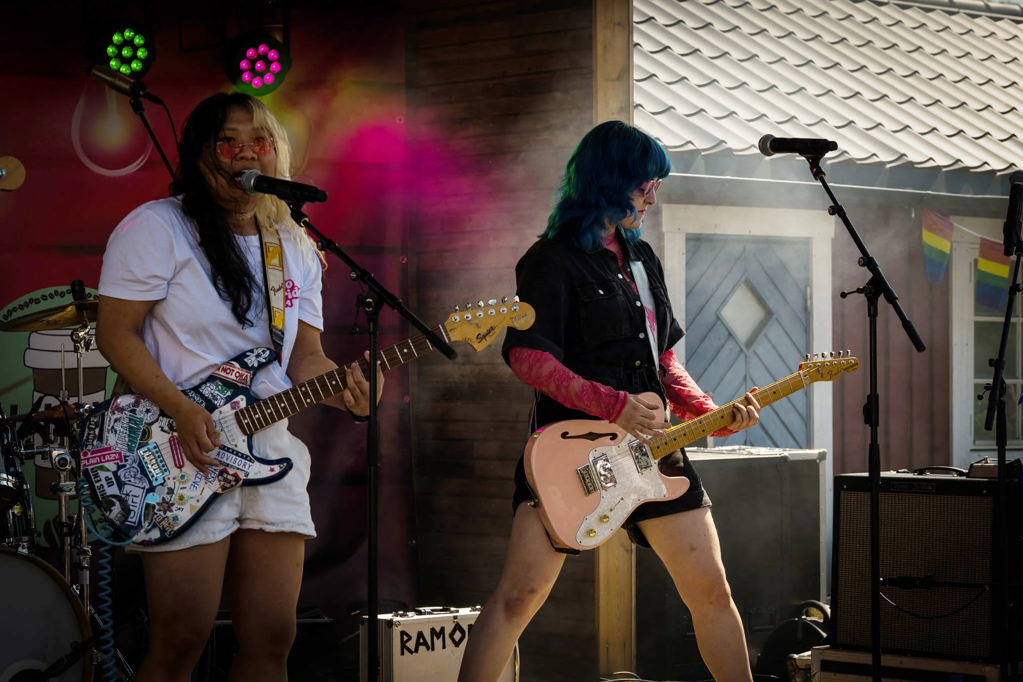 To kvinner spiller elektriske gitarer på en scene under en konsert.