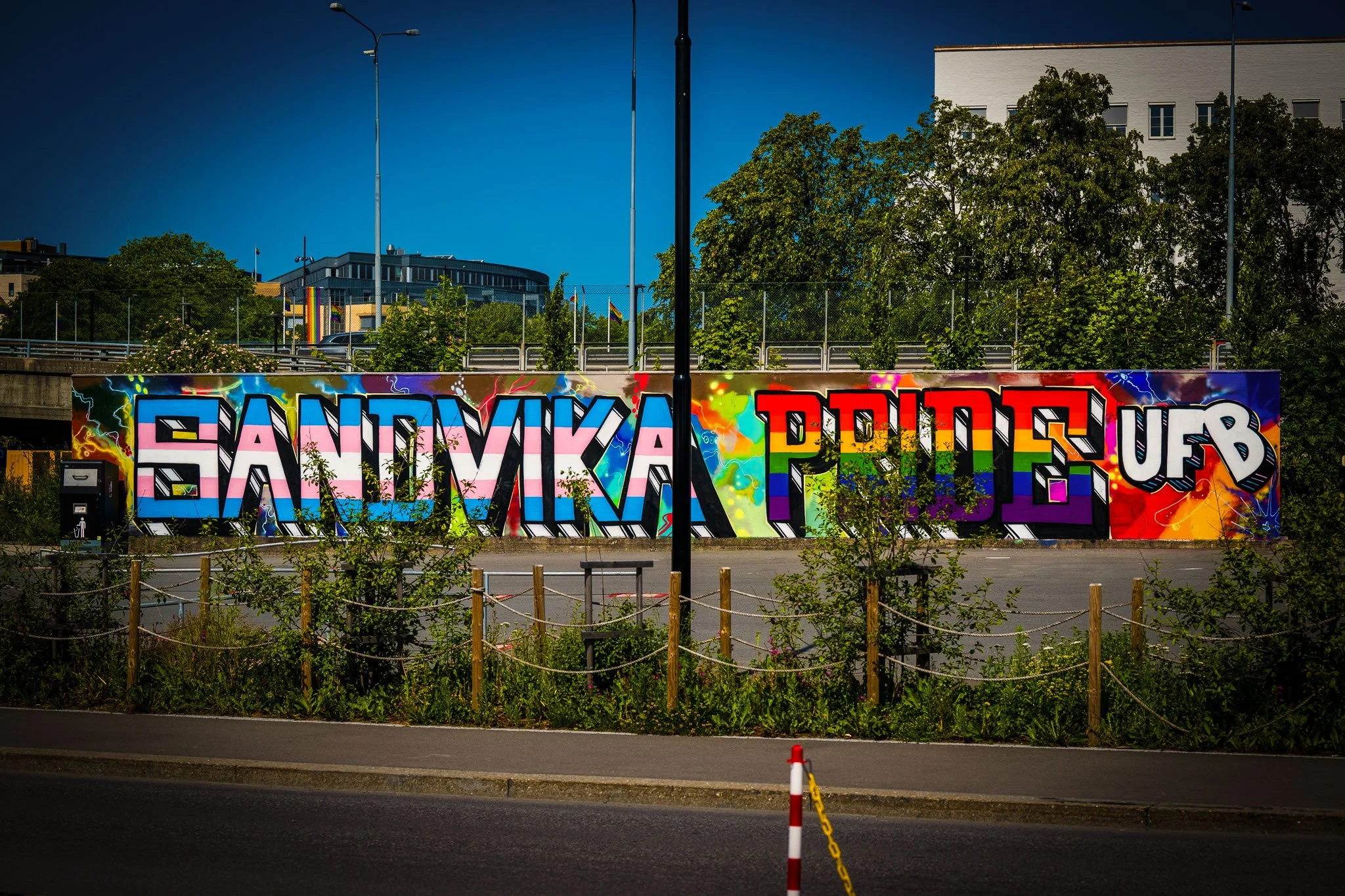Graffiti med teksten "SANTVIKA PØTE UP" på en vegg, omgitt av grønne busker og trær.