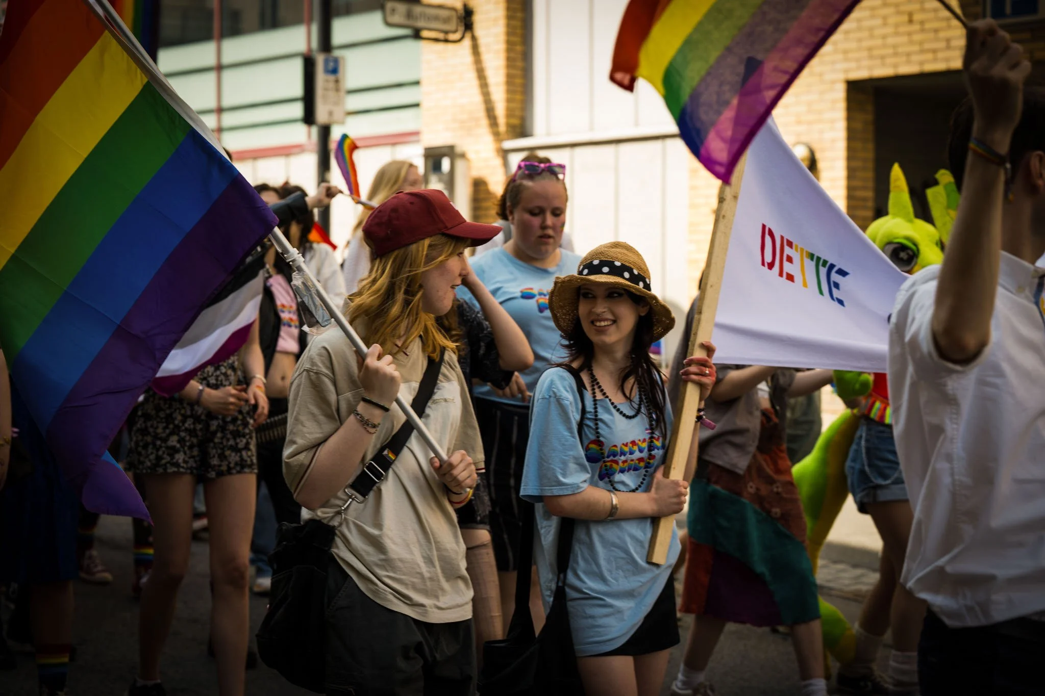 Folk som deltar i parade, noen holder regnbuefargede pride-flagg, og en person har en flagg med teksten "DIXTIE" på.