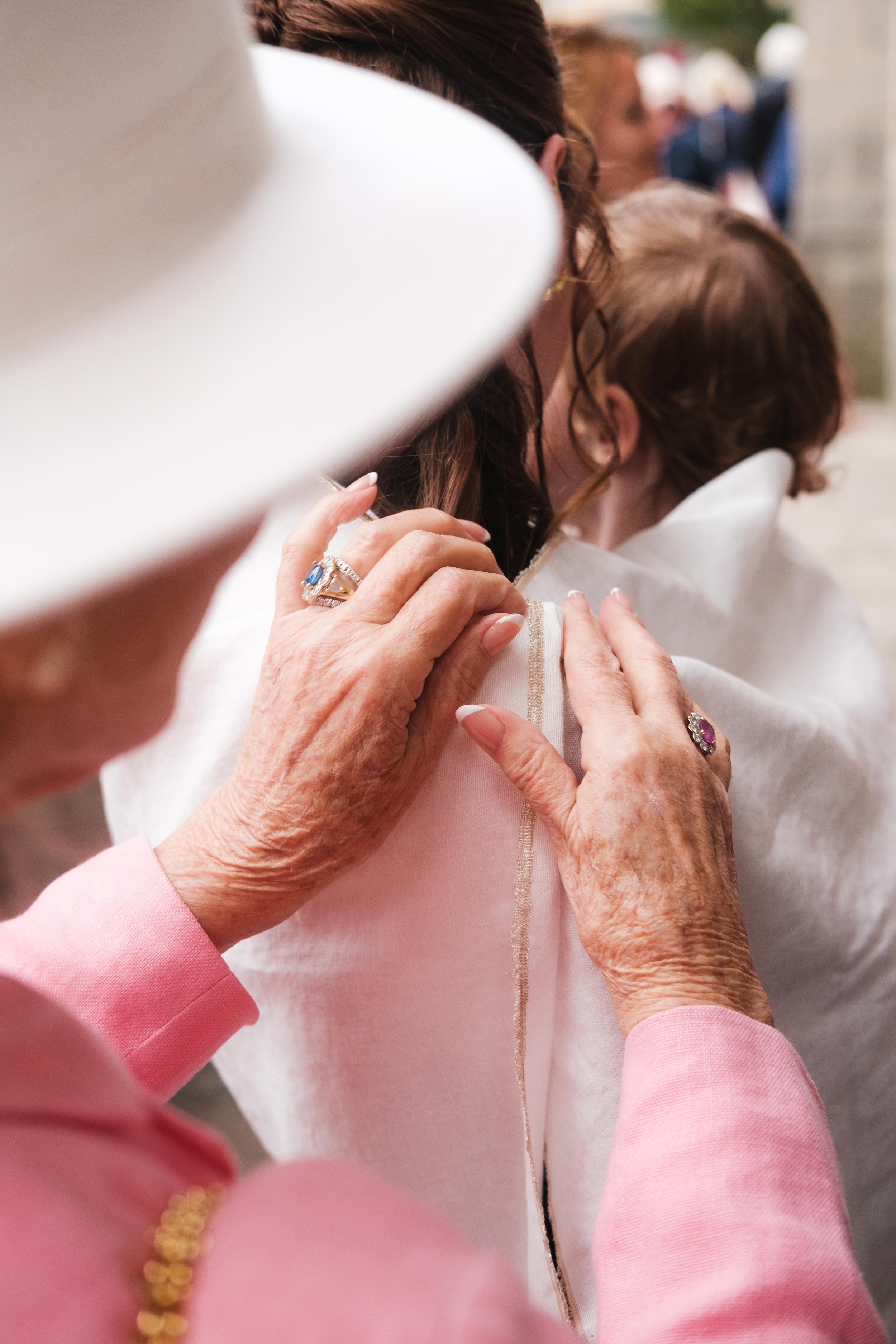 Les mains de la grand-mère de Liv  qui replacent l'habit blanc de baptême avant la cérémonie