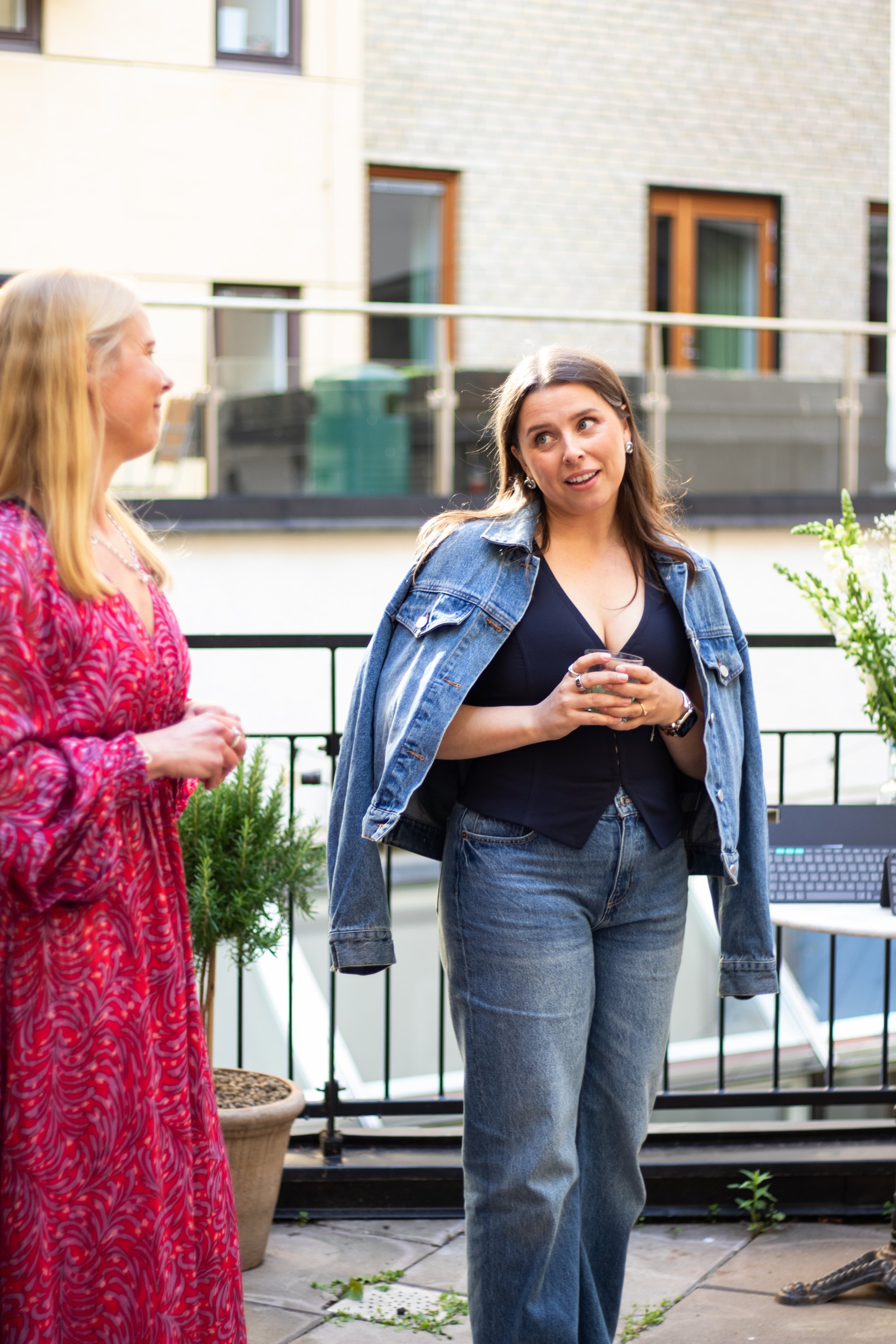 Event photography in Stockholm. Outside venue, sunny after-work event for a tech-company. Swedish influencer hosting with branded drinks and goodie-bags for guests. Hosts welcoming guests to the event. 