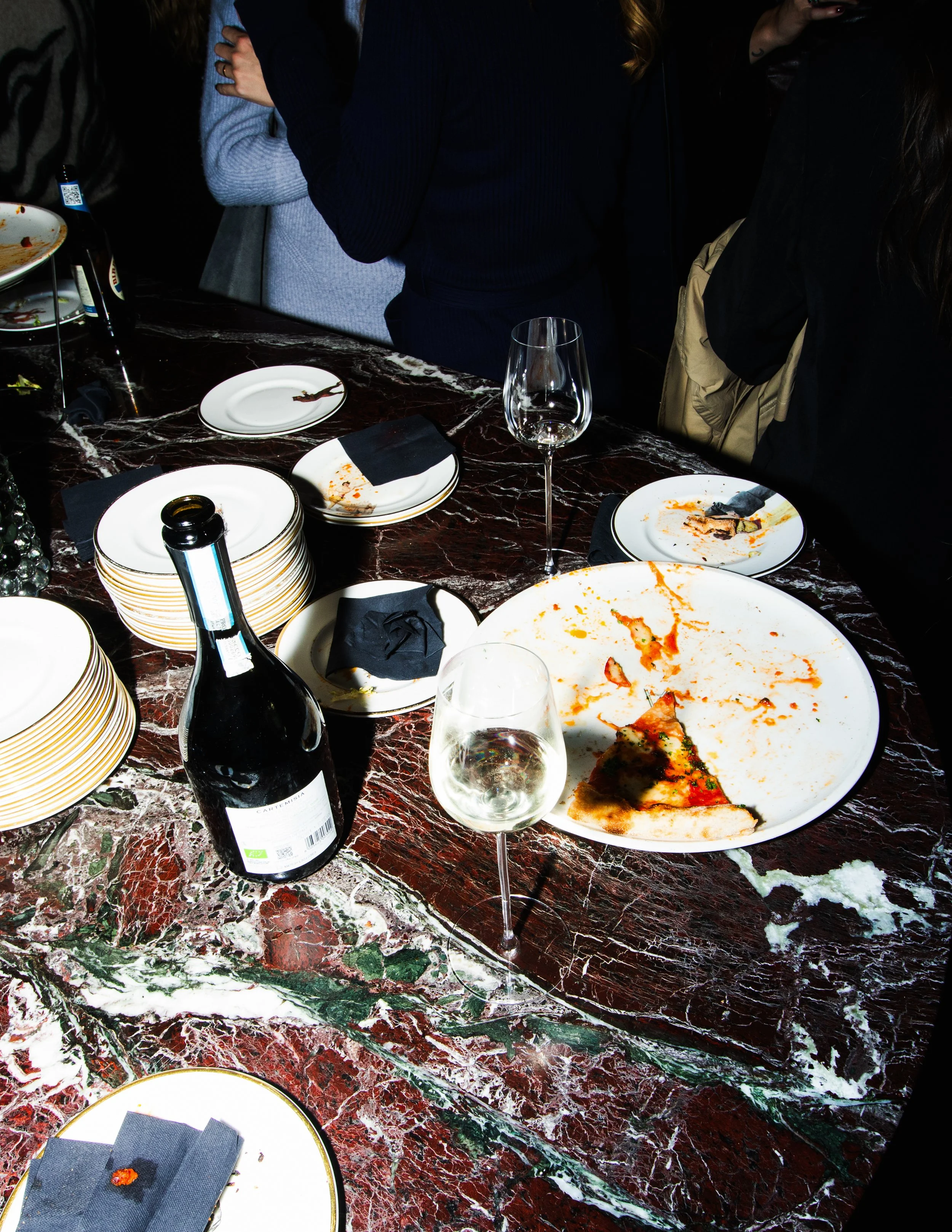 Event photography Stockholm. Marble table with half eaten pizza and champagne bottles. Flash photography.