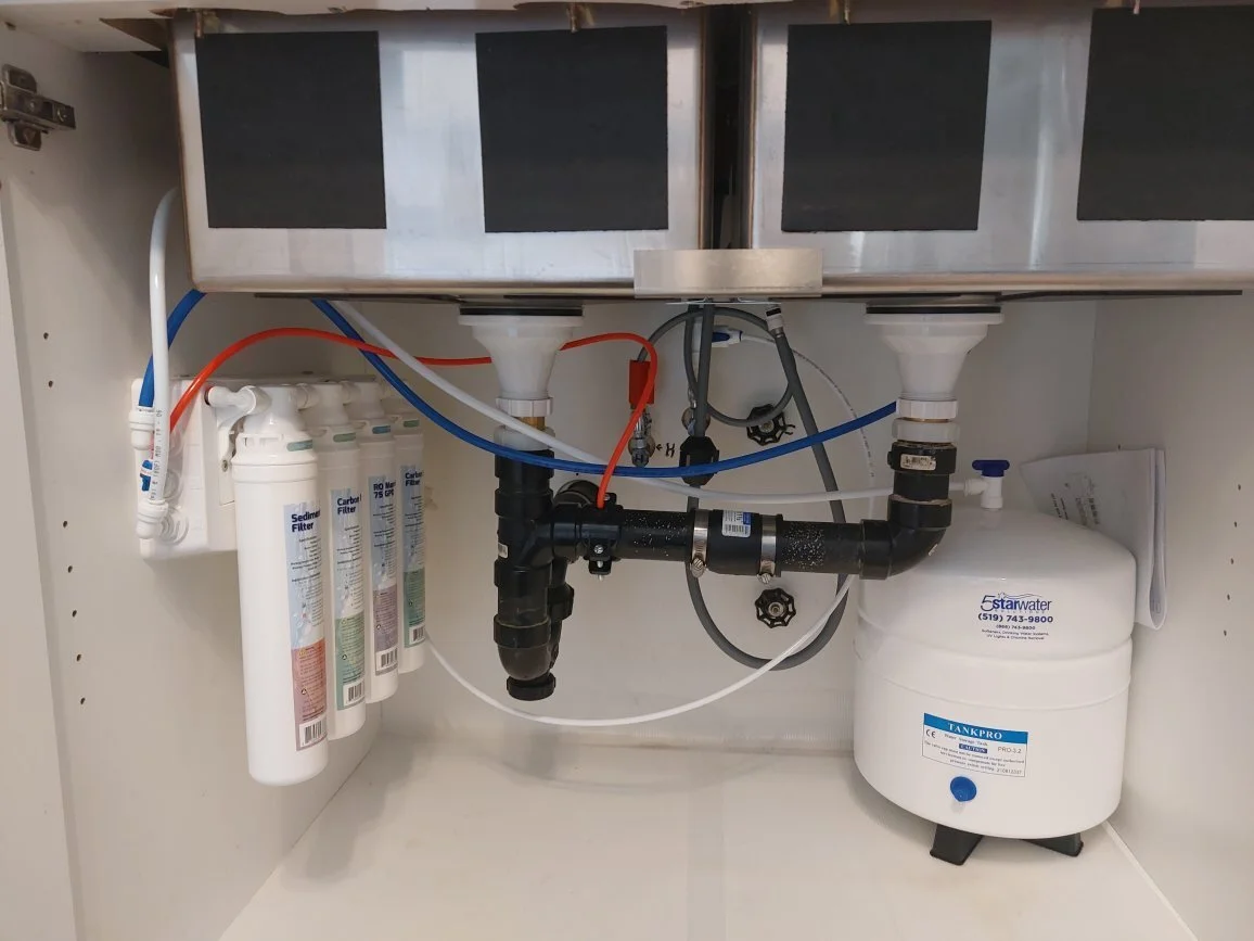 An image of an AquaFlo QCRO Reverse Osmosis Drinking Water System installed underneath a kitchen sink.