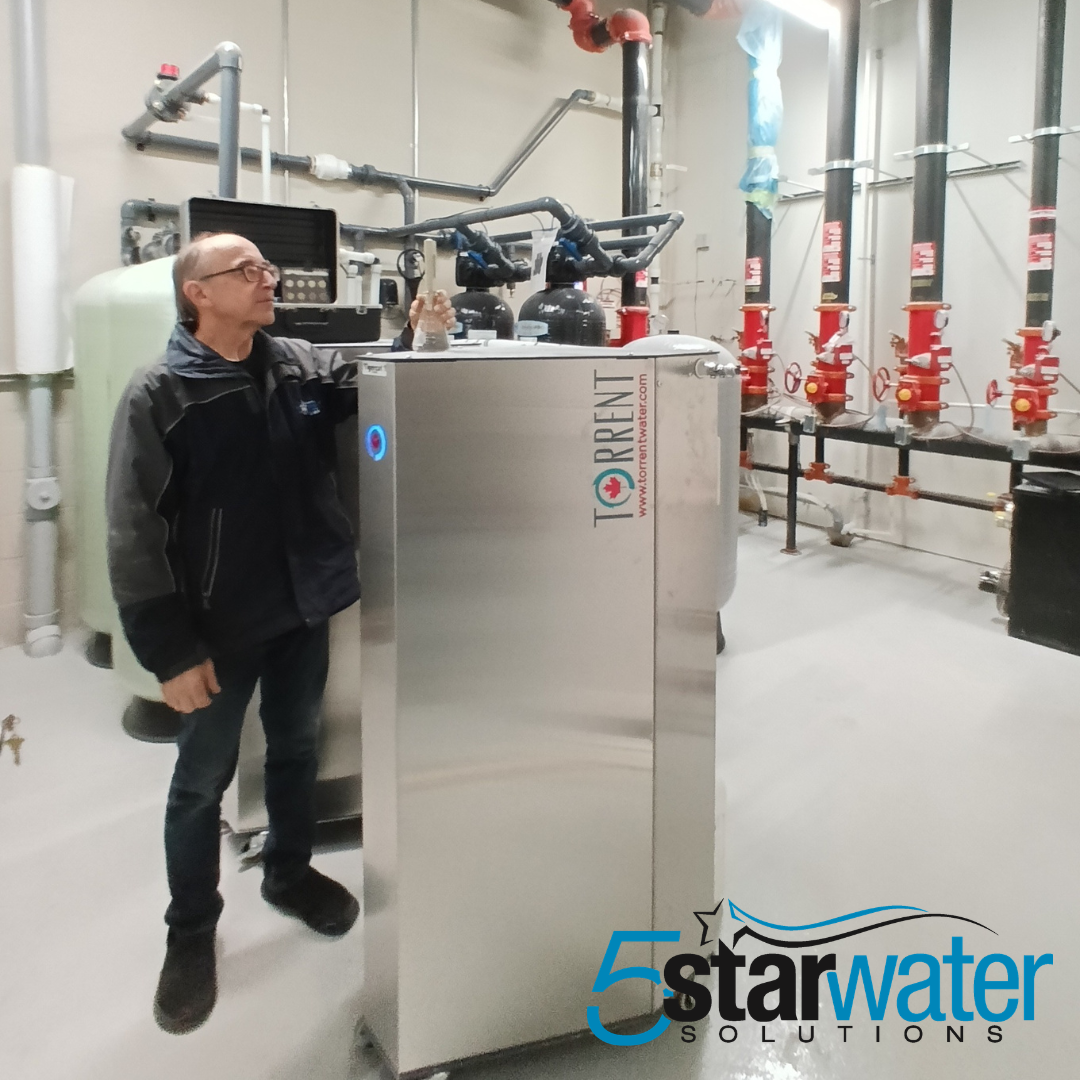 An image of a man standing beside a Torrent 9000 Commercial Water Softener with the 5 Star Water Solutions logo in the bottom right corner.