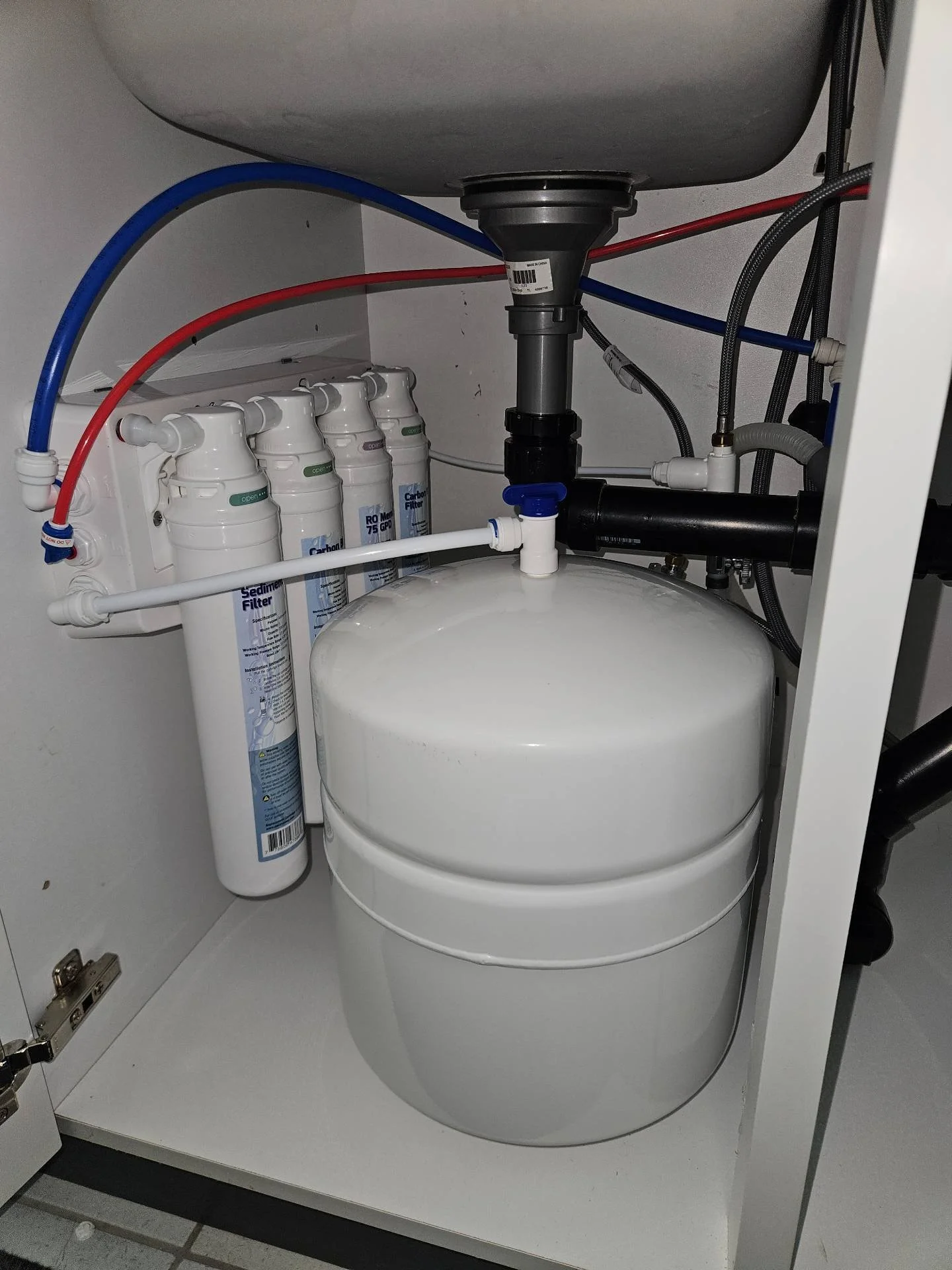 An image of an AquaFlo QCRO Reverse Osmosis Drinking Water System installed underneath a kitchen sink.